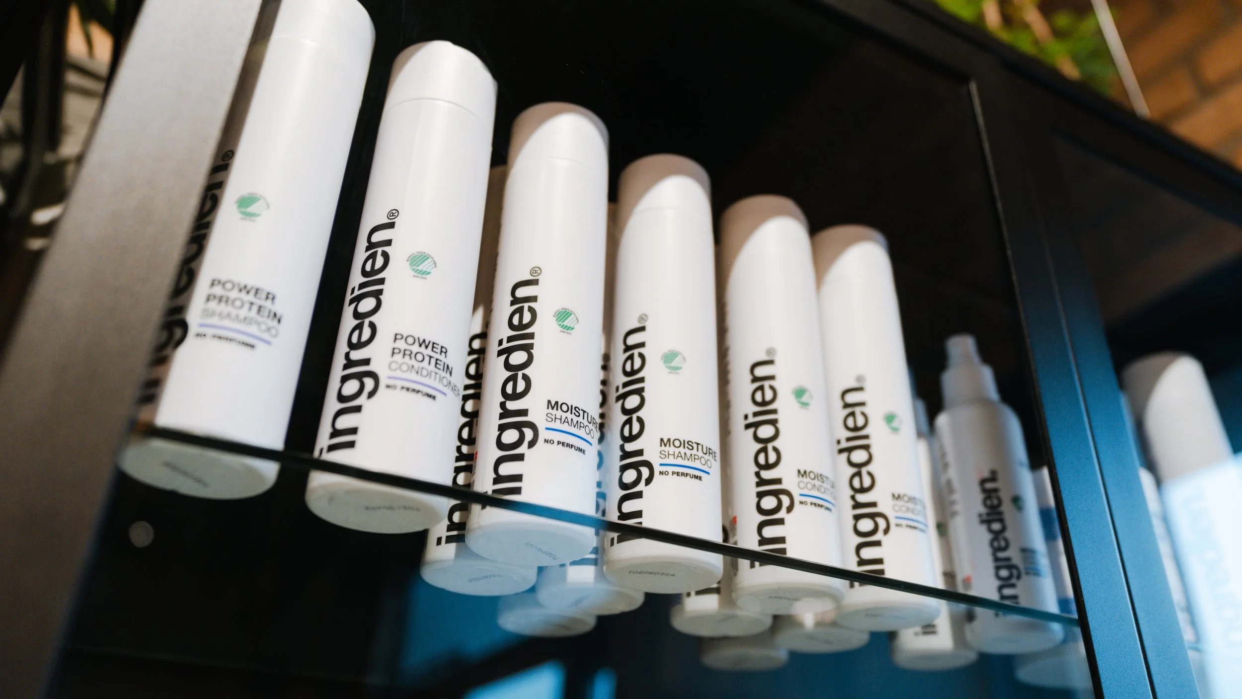 Hårplejeprodukter i hvid emballage med mærket Ingredien på en hylde.