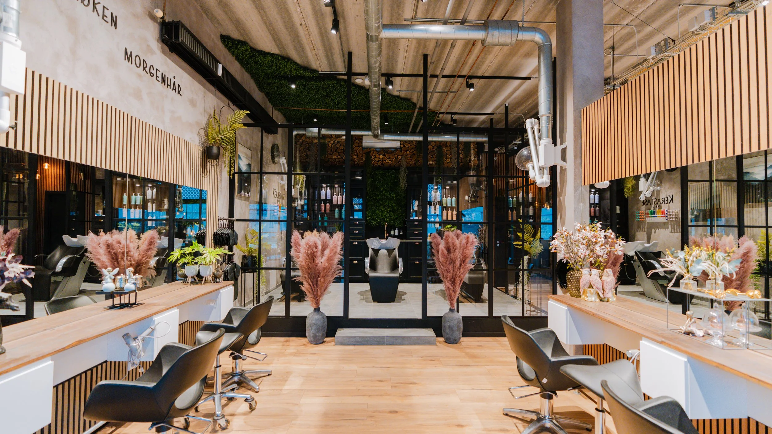 Indretning af frisørsalon med barberstole, spejle, planters, og dekorative elementer i moderne stil.