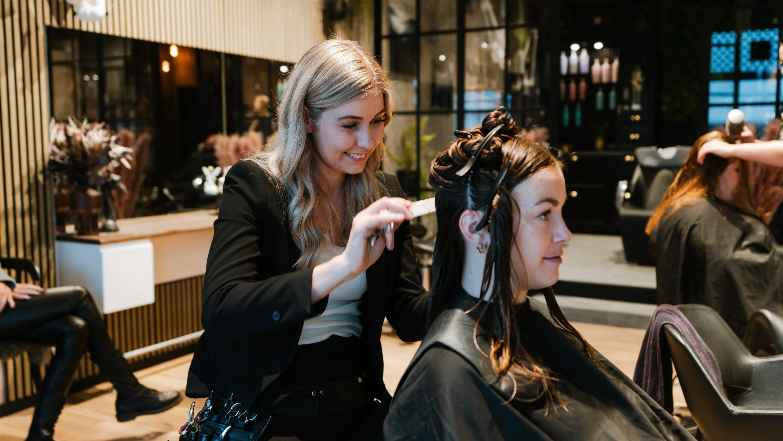 En frisør, der farver en kvindes hår i en salon om aftenen.