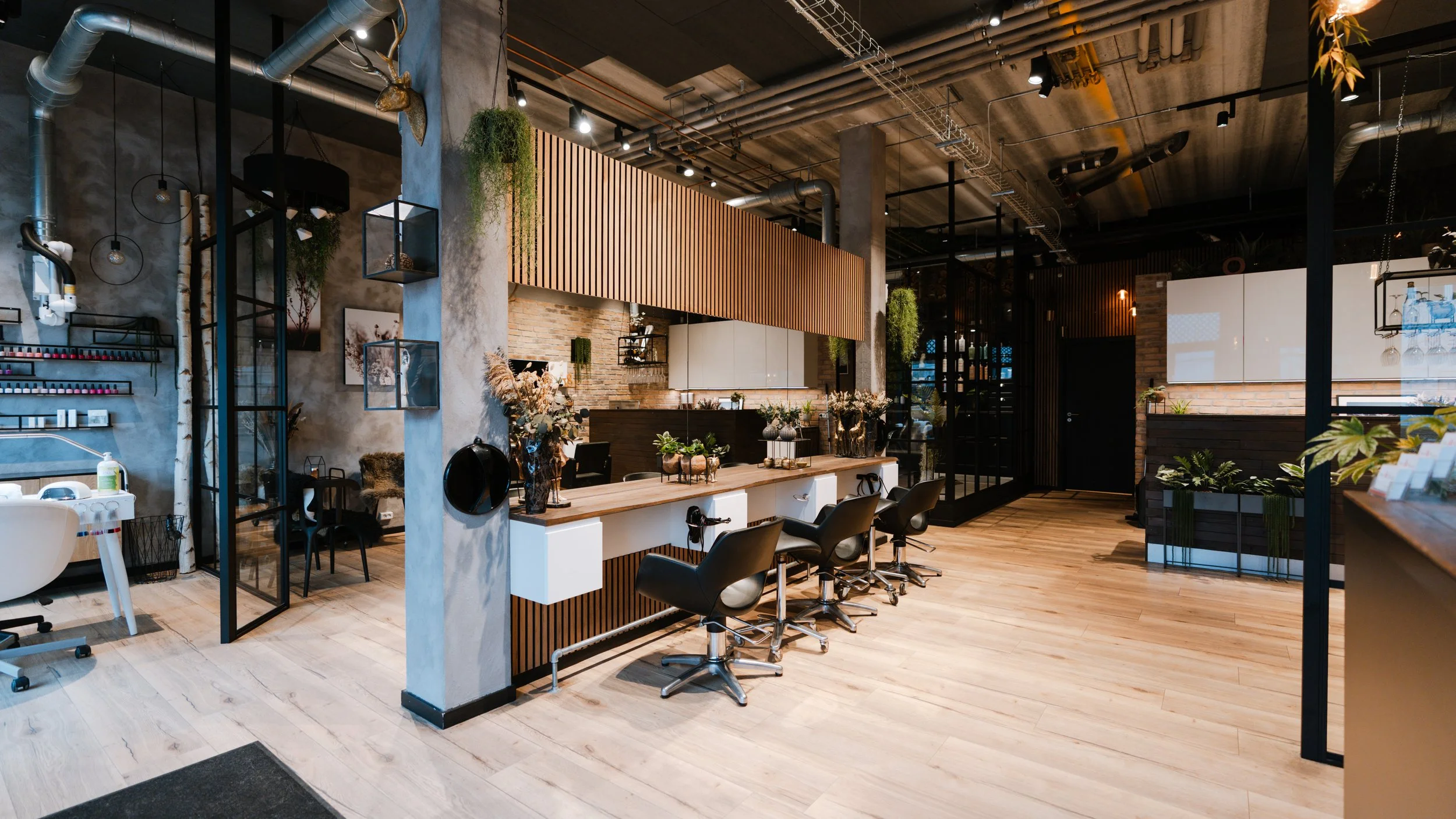 Moderne frisørsalon med sorte og hvide farvetemaer, træborde og grønne planter