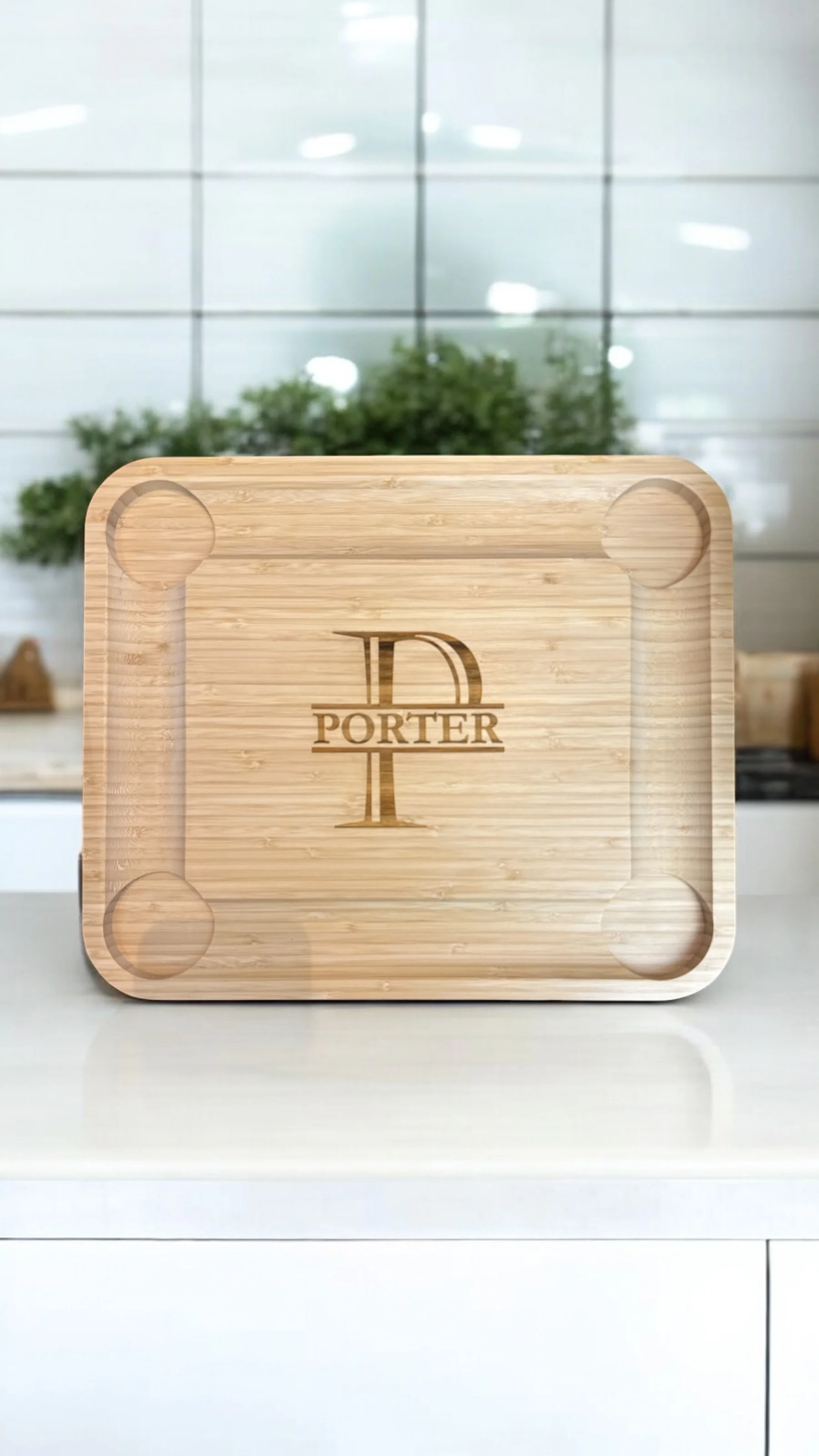 A wooden serving tray with the word "PORTER" and a large letter "P" engraved on it, placed on a countertop in a bright, modern kitchen.