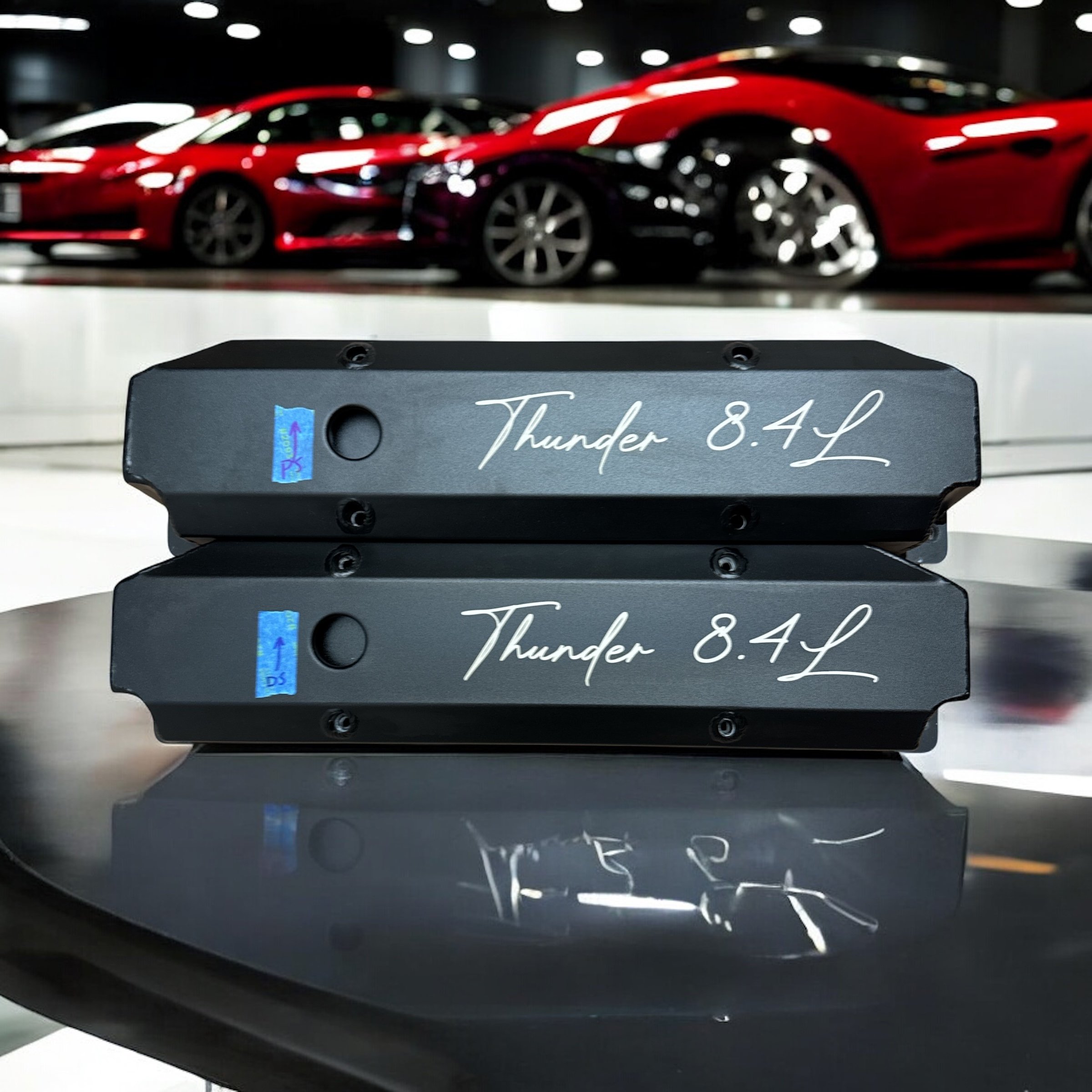 Close-up of a black electronic device with the words "Thunder 8.4L" written on it, with a display showing some icons and a reflective surface below.