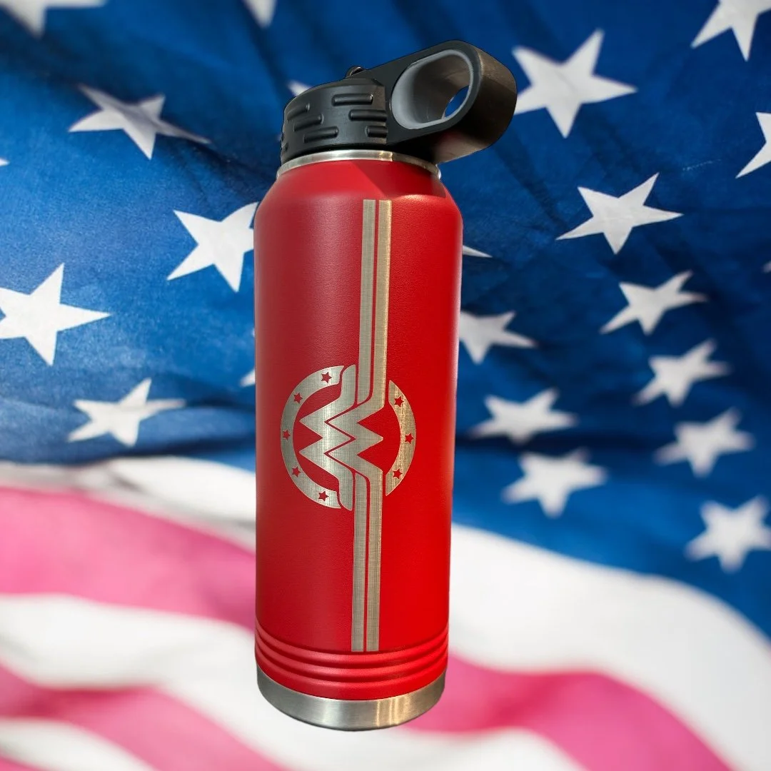 A red water bottle with a Breaking Bad-inspired logo, featuring a stylized blue meth molecule with a crack, placed in front of an American flag background.