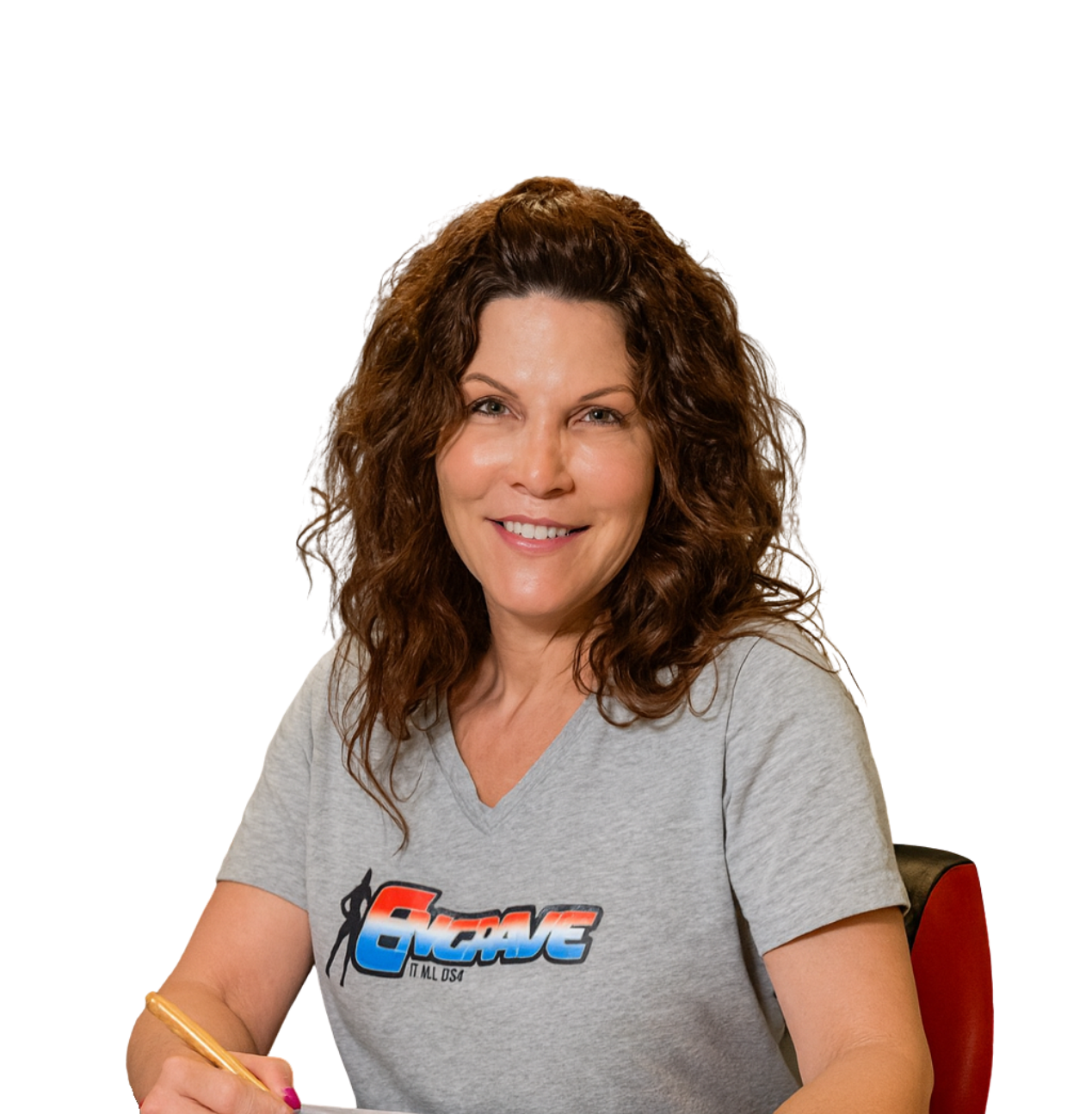 Smiling woman with curly brown hair sitting at a table, wearing a gray T-shirt with a Rockstar logo, holding a pen.