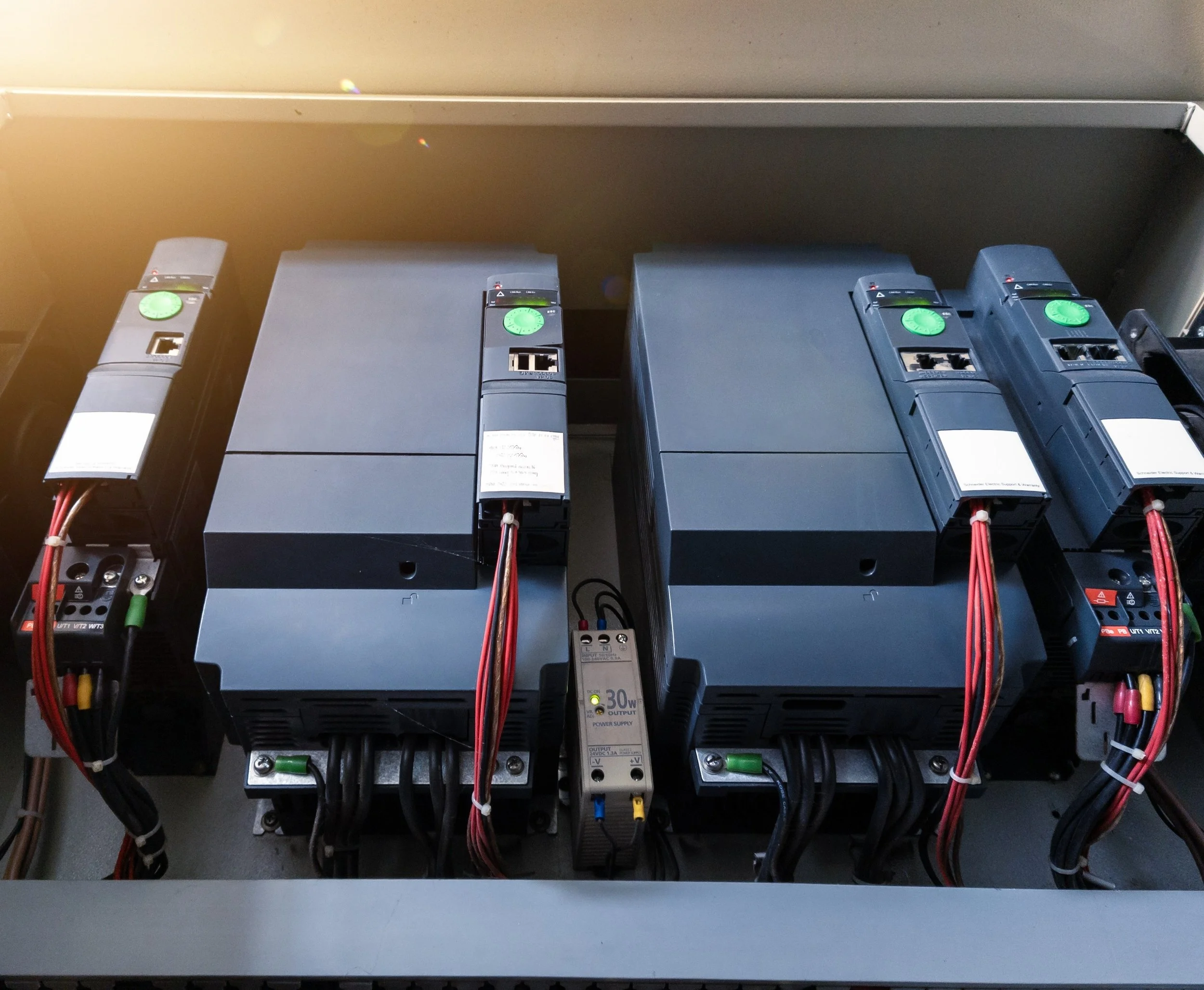 Electrical system with two large circuit inverters, wiring, and a power supply in an industrial setting.