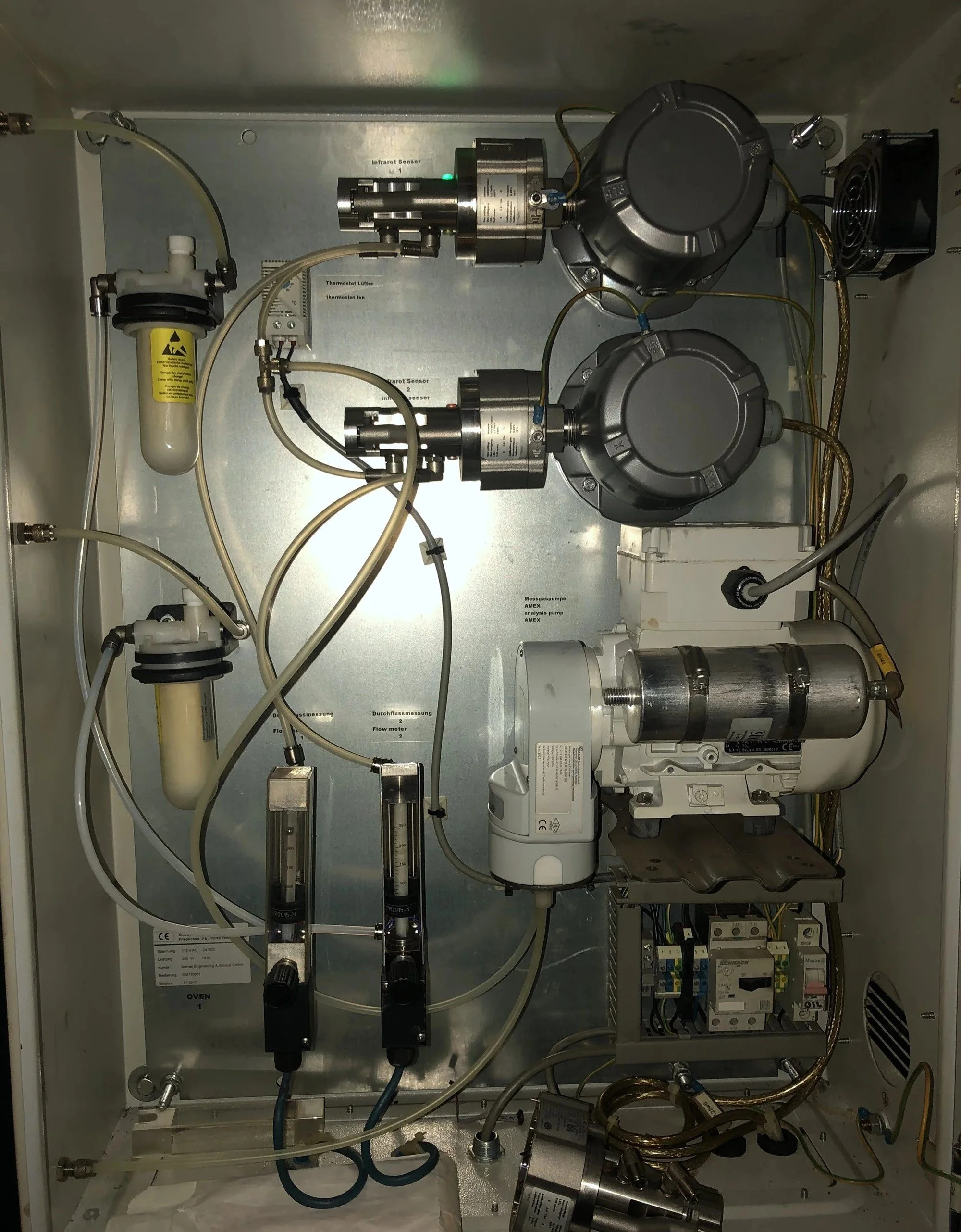 Inside view of a scientific or industrial machine with various pipes, sensors, and electronic components.