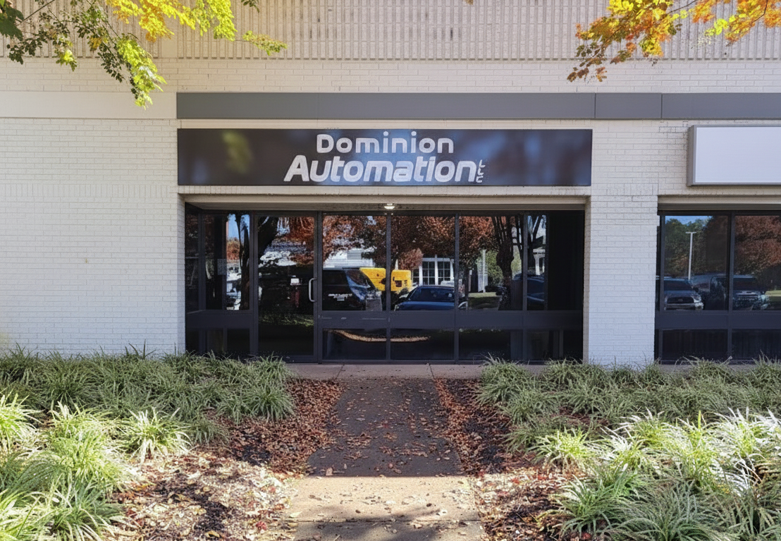 storefront with a sign that reads 'Dominion Automation' with a walkway leading to the entrance, surrounded by landscaping and trees.