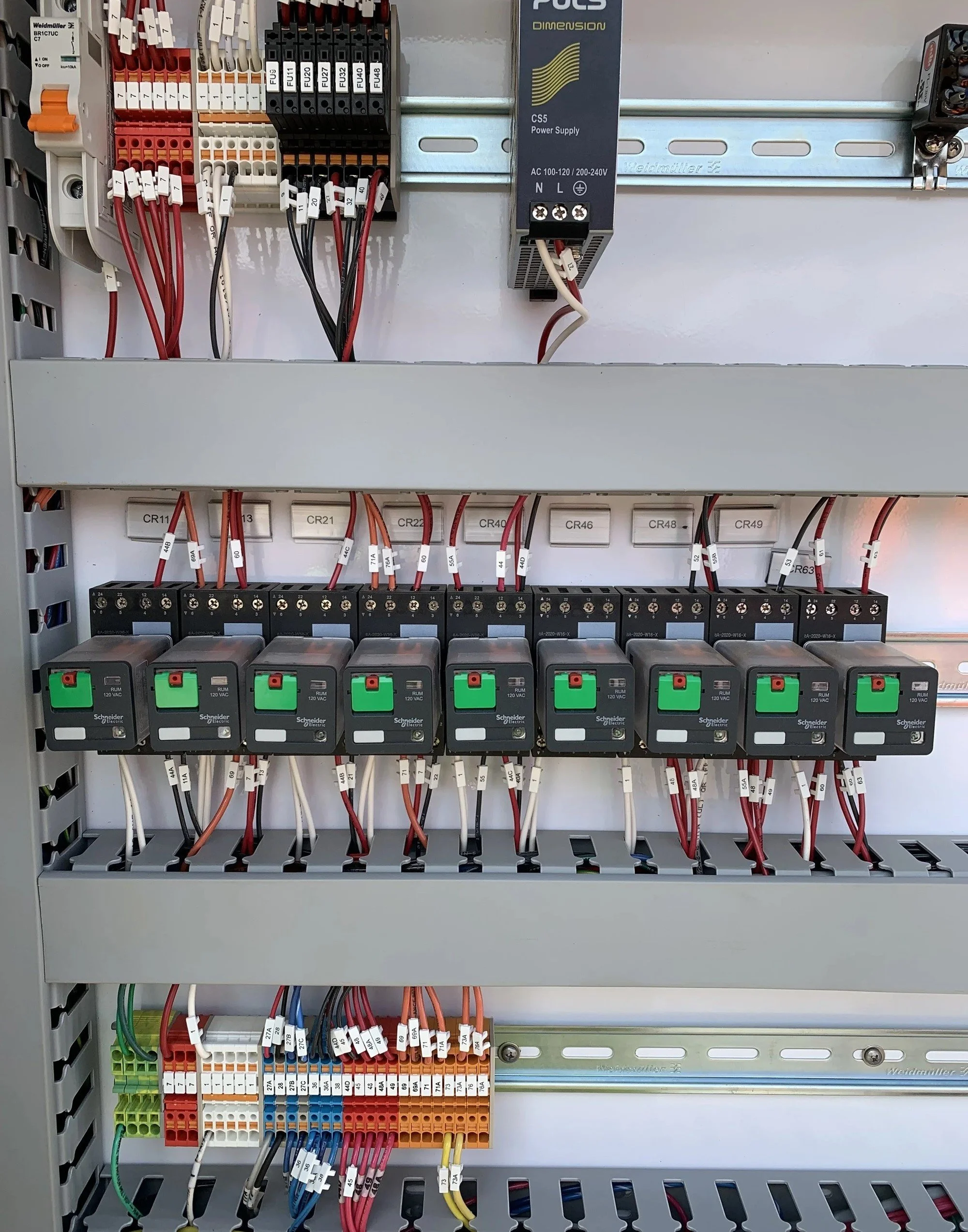 An electrical control panel with various wires and components, including relays, power supply, and terminal blocks.