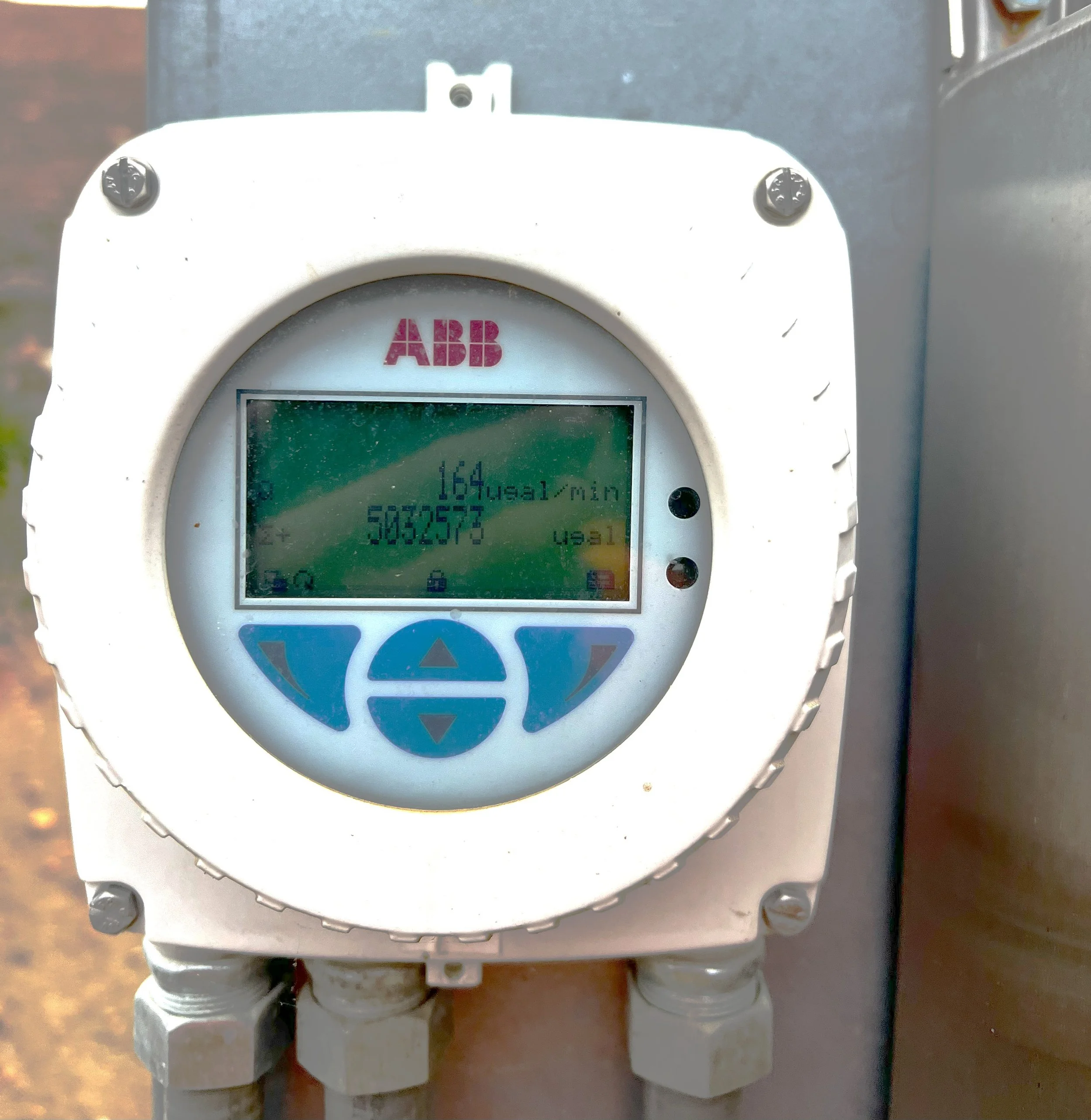 An ABB digital electronic meter displaying an energy consumption of 164 kWh, with additional numbers and indicators on its screen, mounted on an outdoor electrical panel.