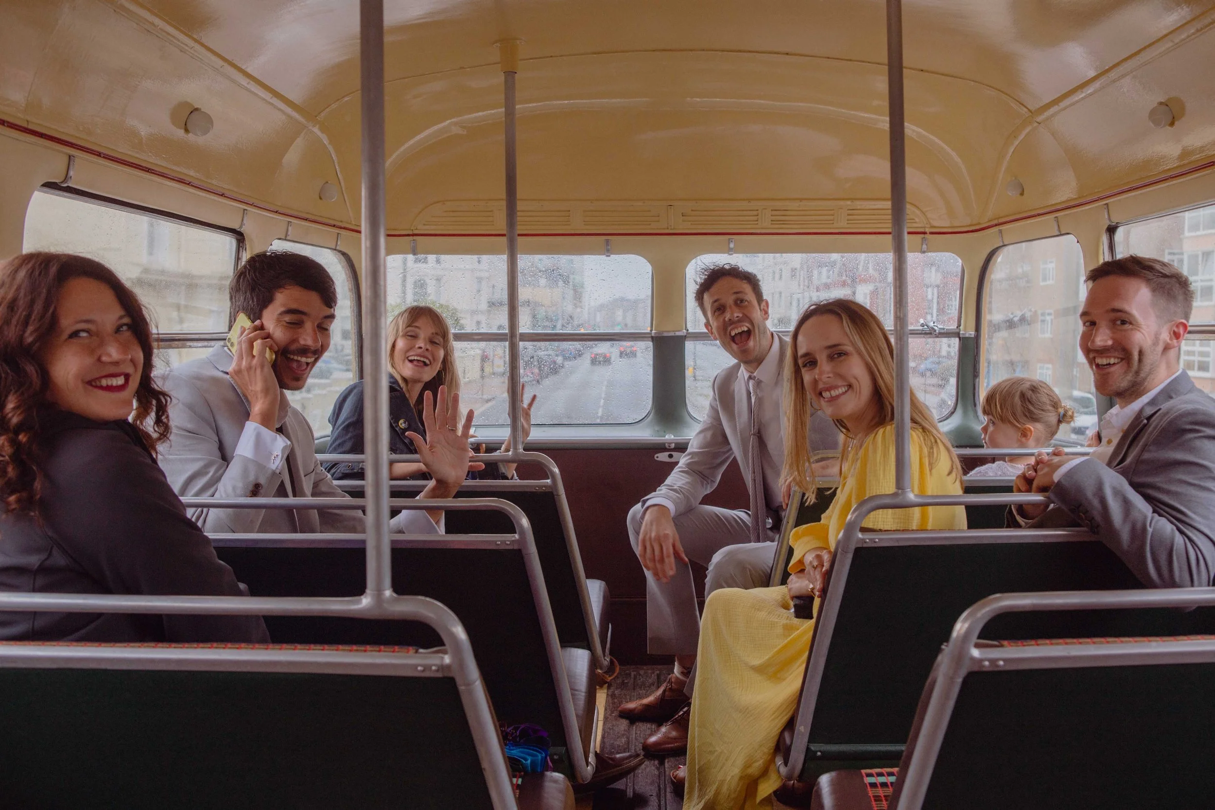 A group of seven people sitting on a bus enjoying a ride, smiling and chatting.