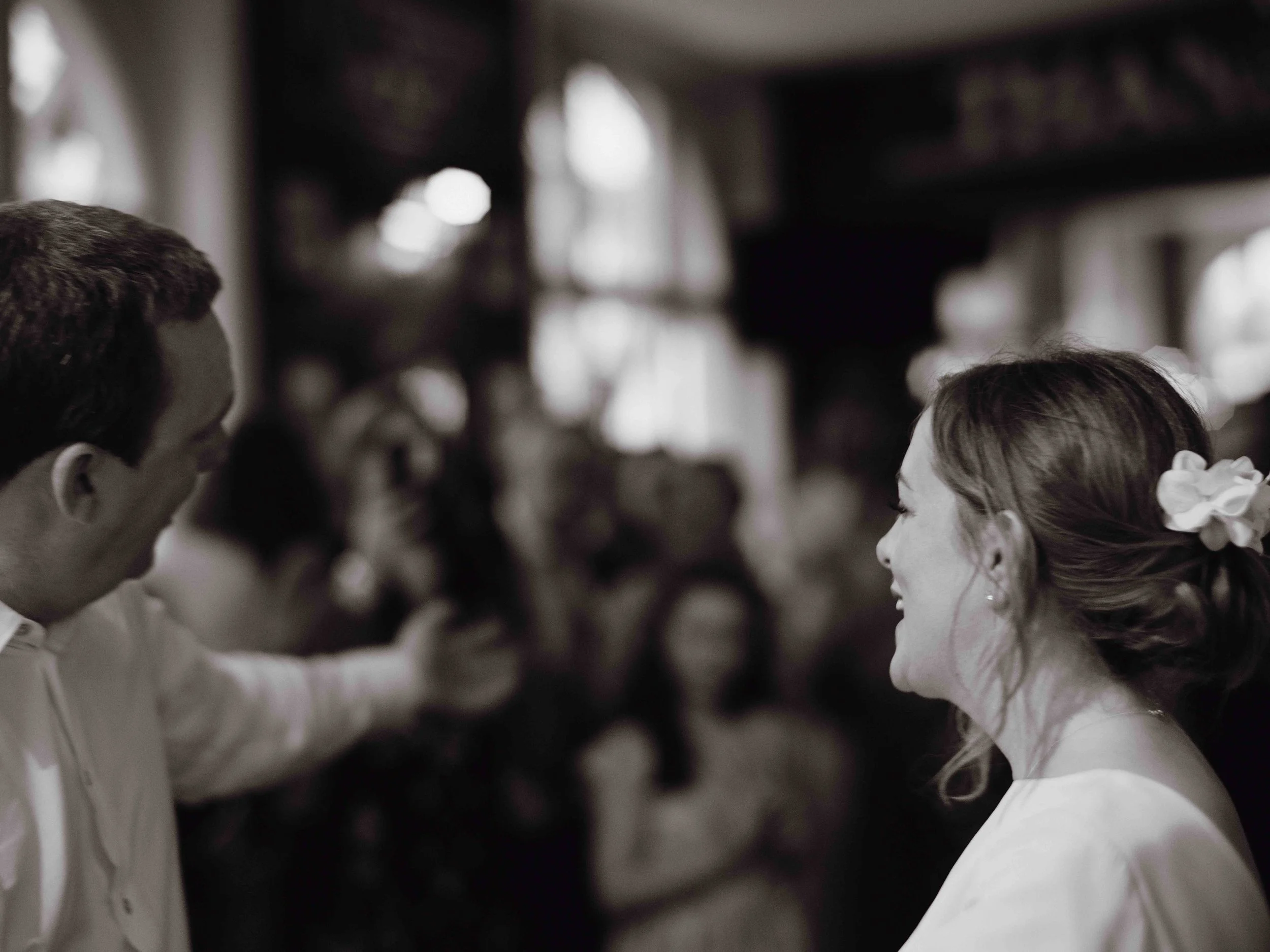 A bride and groom smiling and facing each other at their wedding reception.