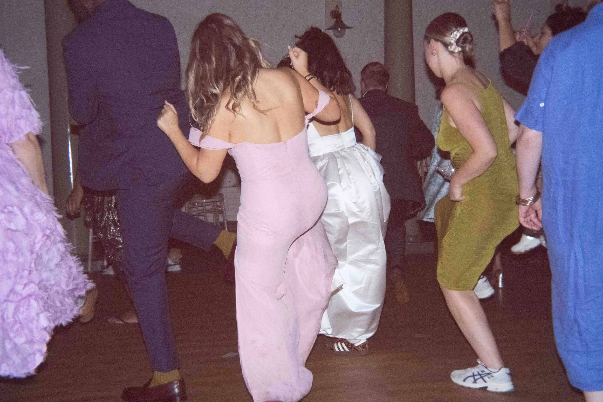 People dancing at a party or celebration, wearing colorful and stylish clothing.