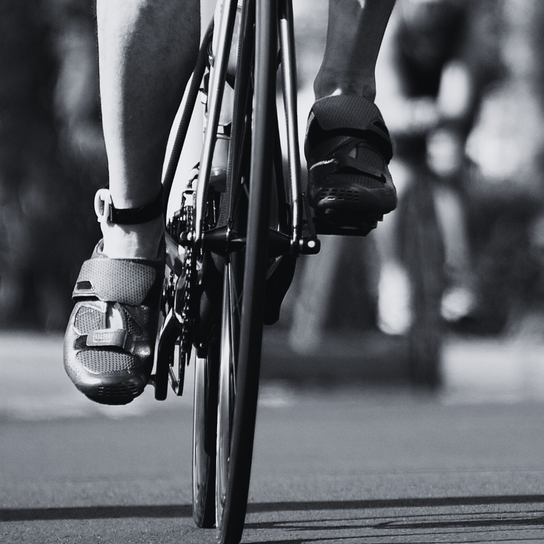 Close-up of a triathlete's legs and feet on a triathlon bike, with the focus on cycling shoes, in black and white.