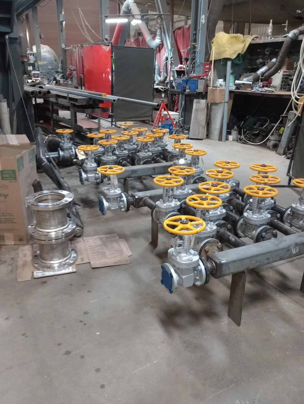 Industrial pipes with yellow valves in a workshop or factory setting.