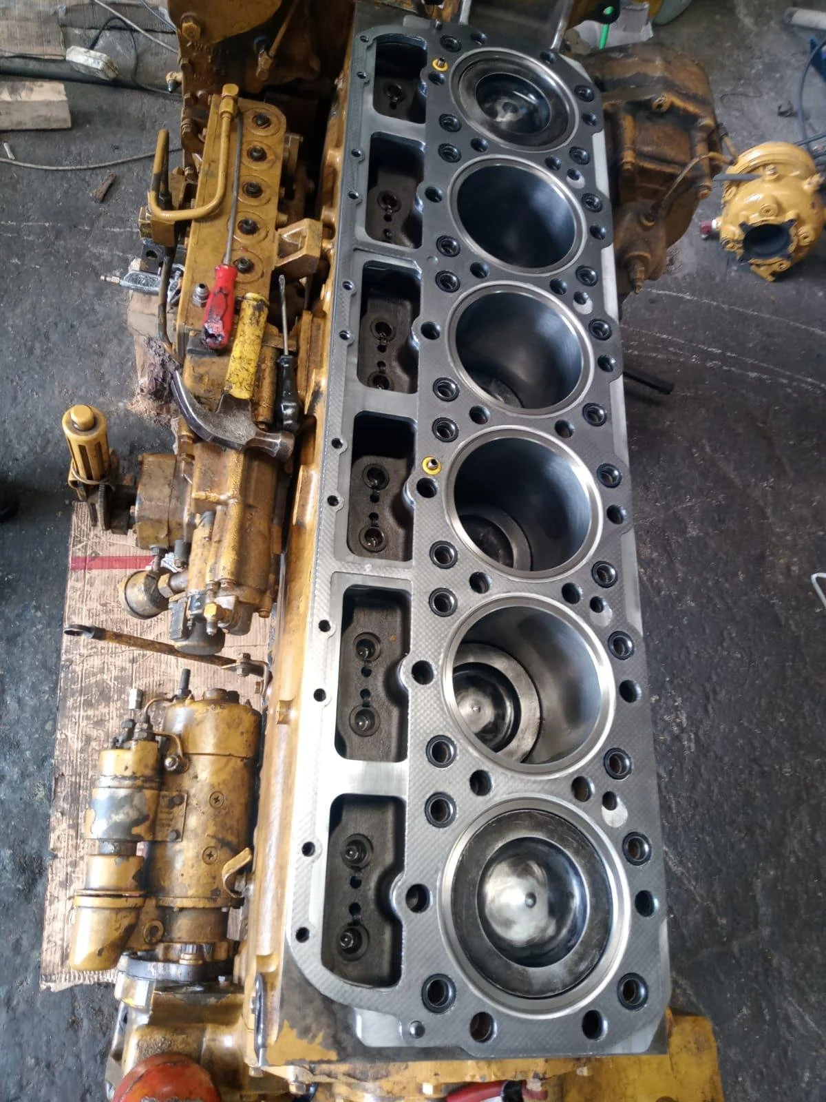 Disassembled engine block with visible cylinders and components in a workshop.