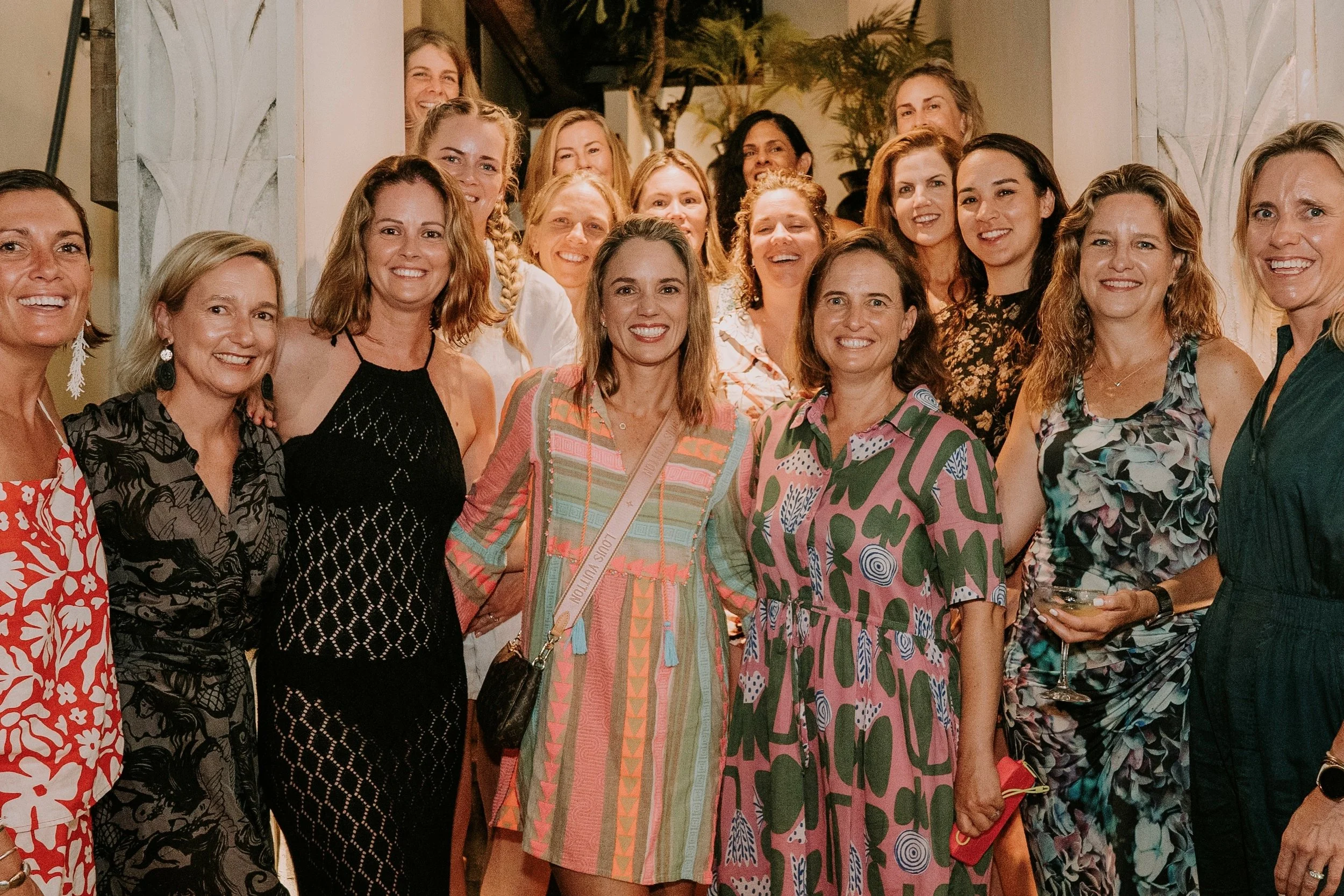 Group of women gathered together indoors, smiling for a photo at a social event or party.