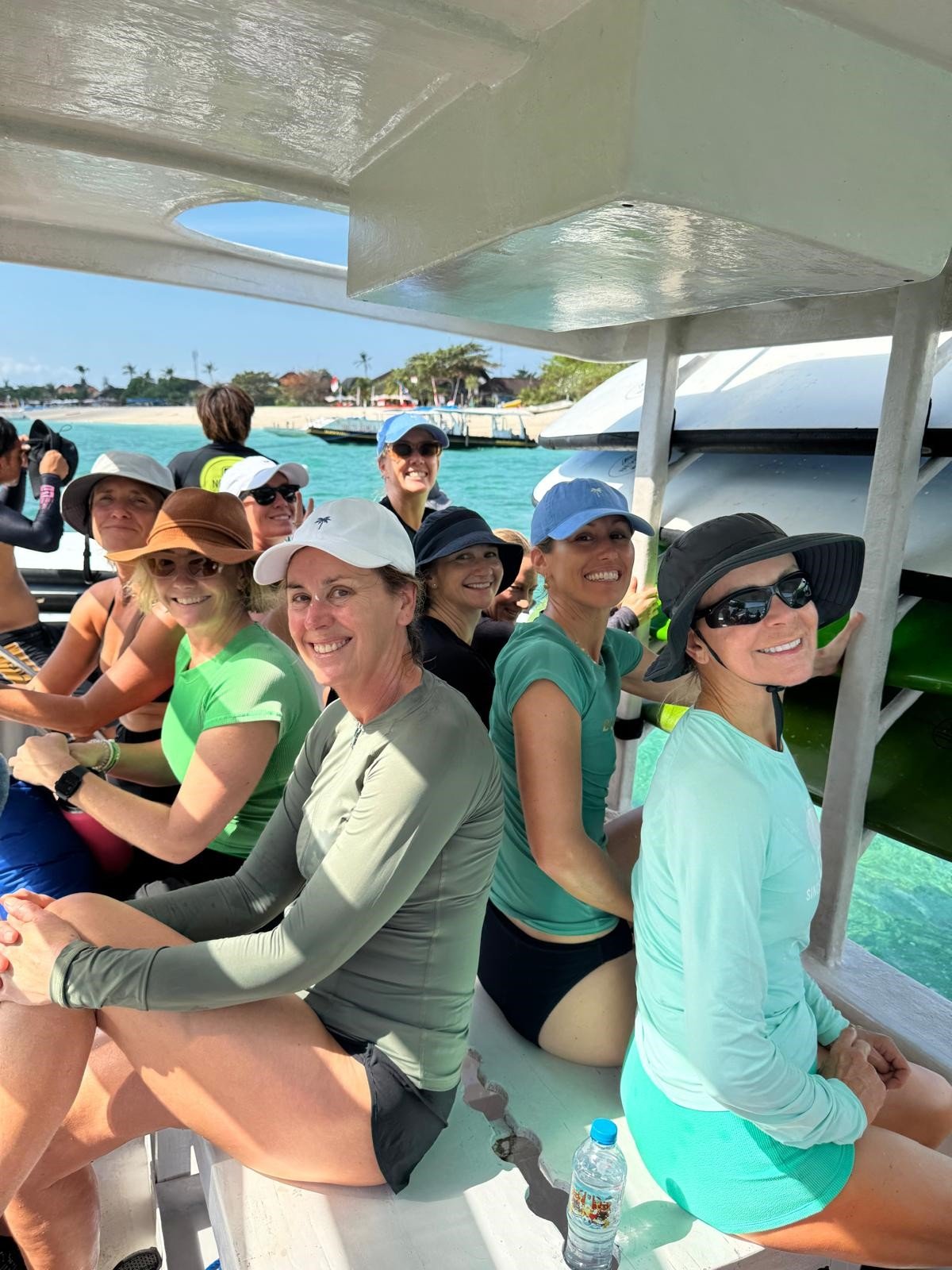 Group of women on a boat tour enjoying sunny weather with clear blue water in the background.