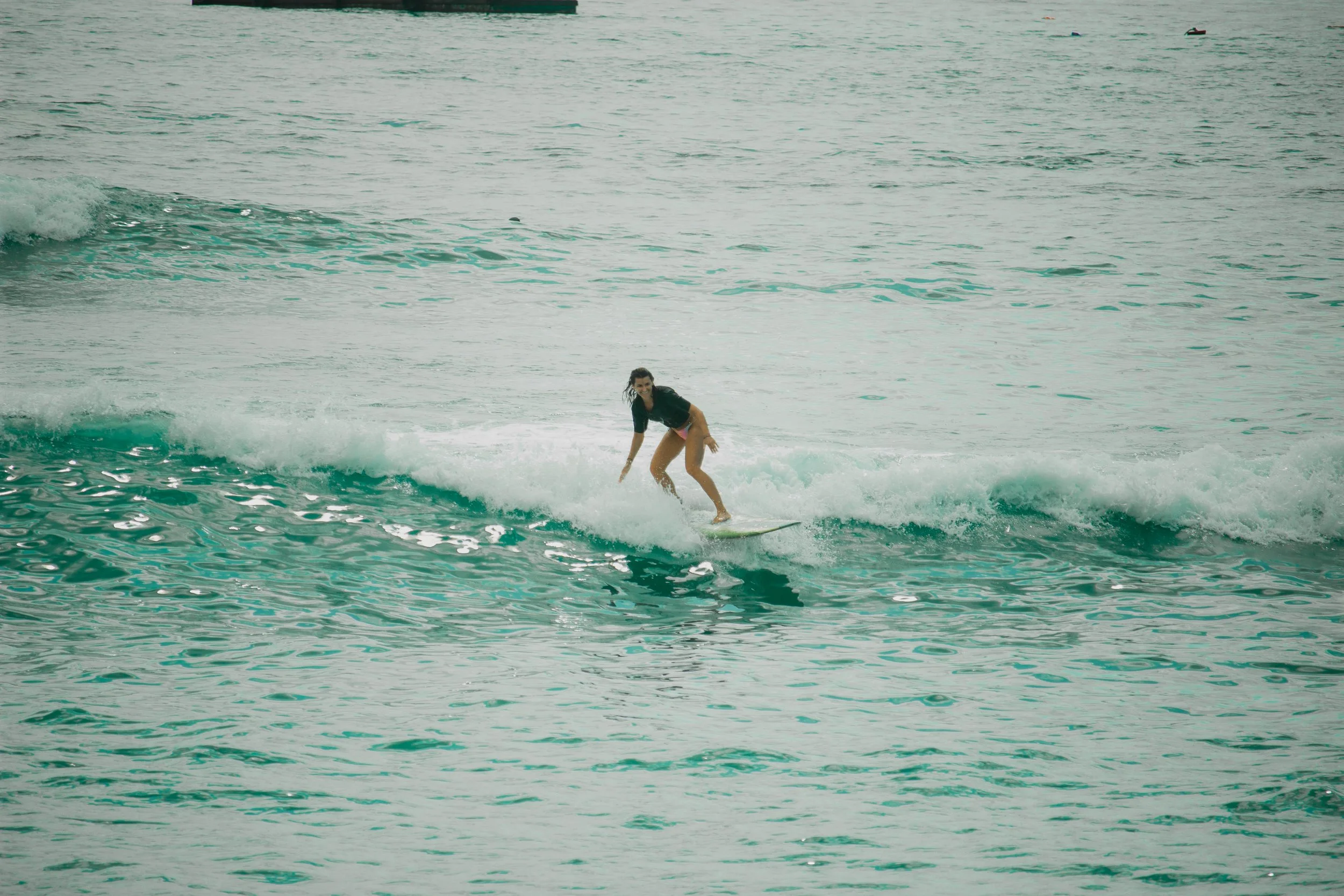 A woman surfing on a small wave in the ocean during daytime