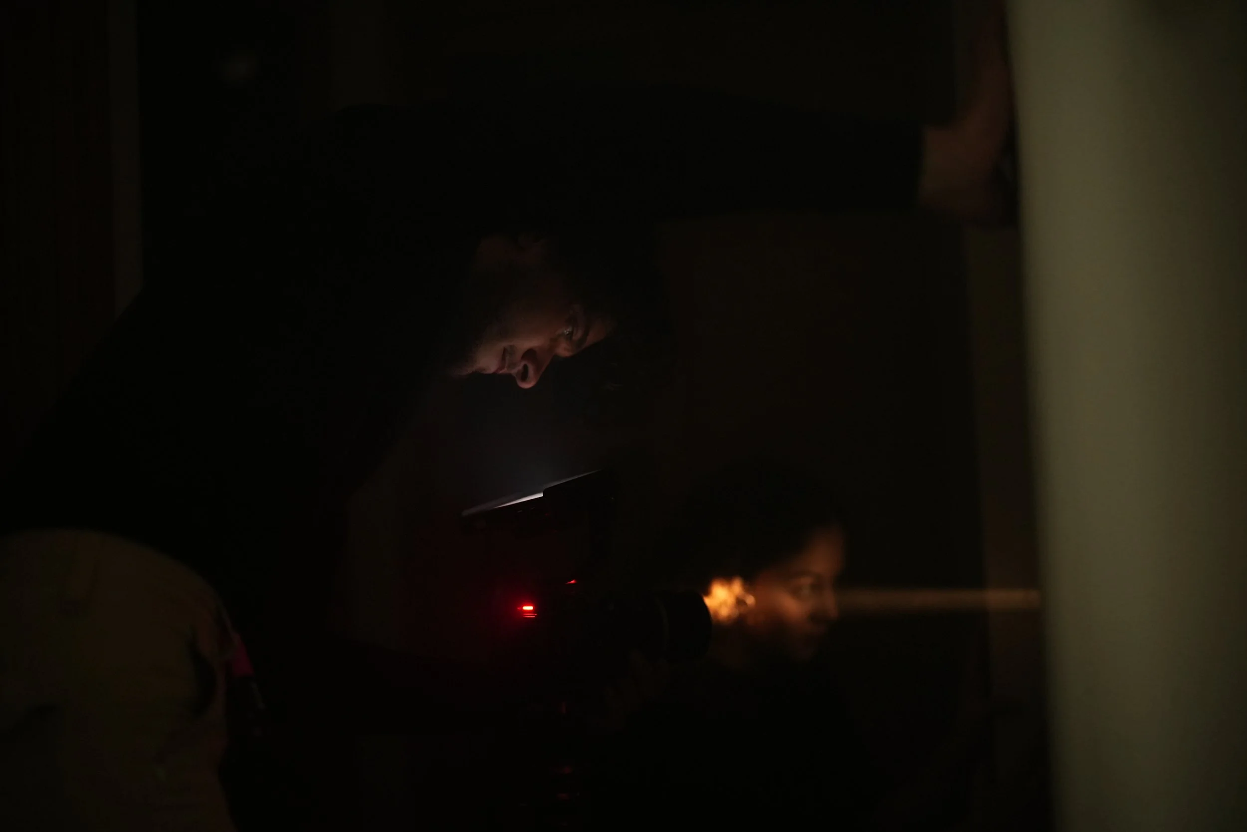 Un homme utilisant un projecteur dans un environnement sombre, projetant une lumière sur un visage féminin.