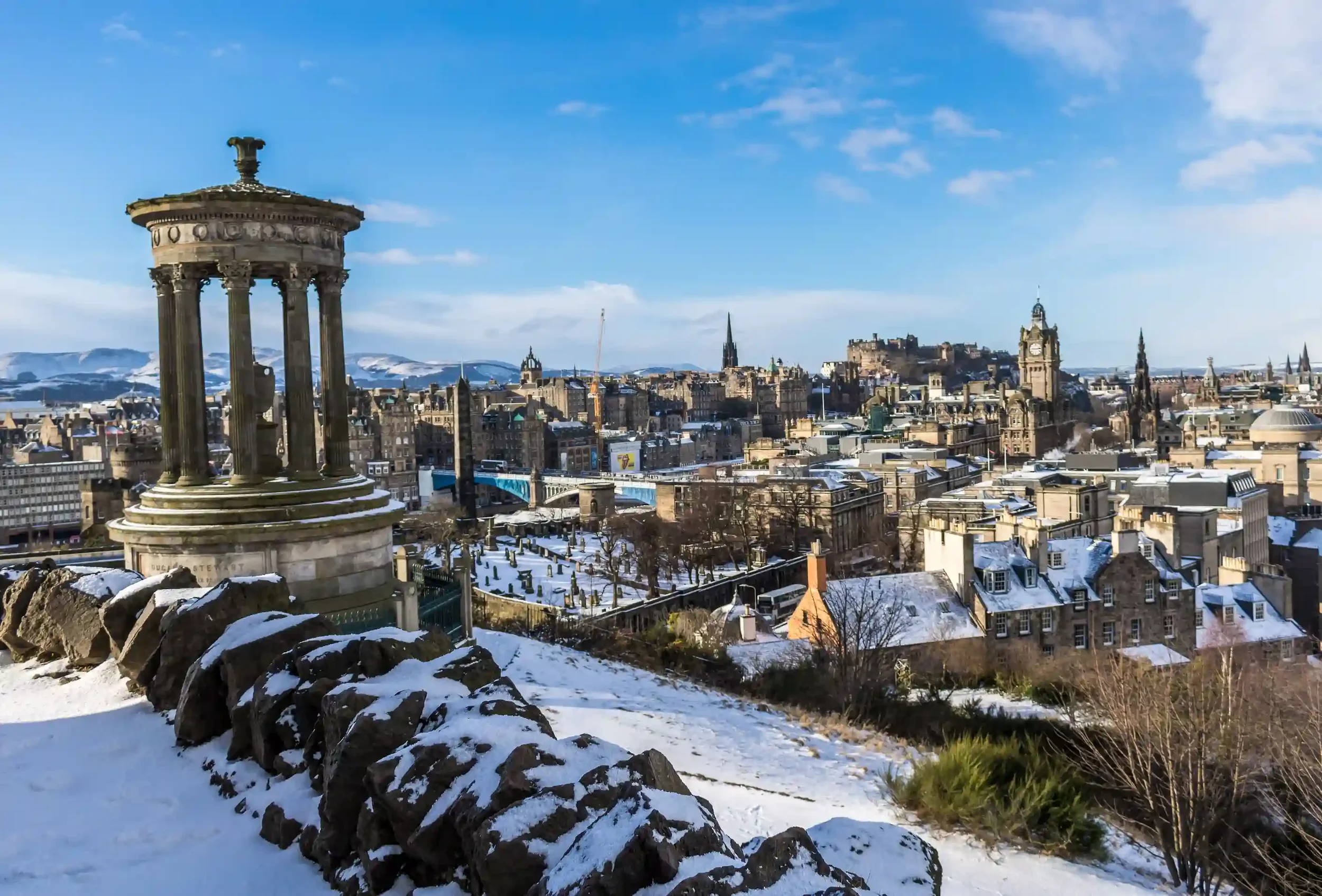 Monument Dugald Stewart sur Calton Hill sous la neige, avec vue sur les toits d'Édimbourg en hiver