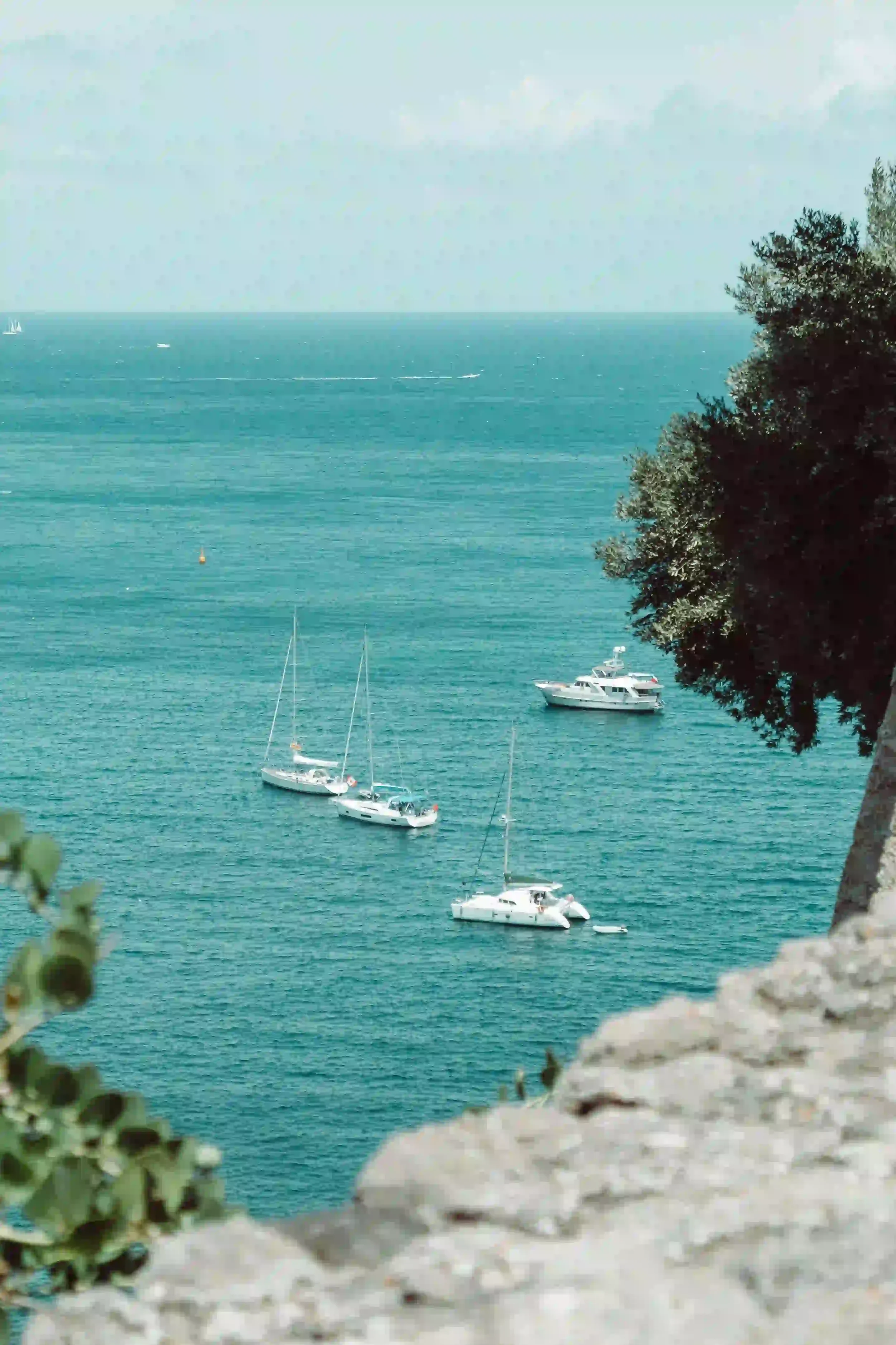 Vue sur la baie d'Ischia depuis les rochers, voiliers au mouillage sur une mer turquoise