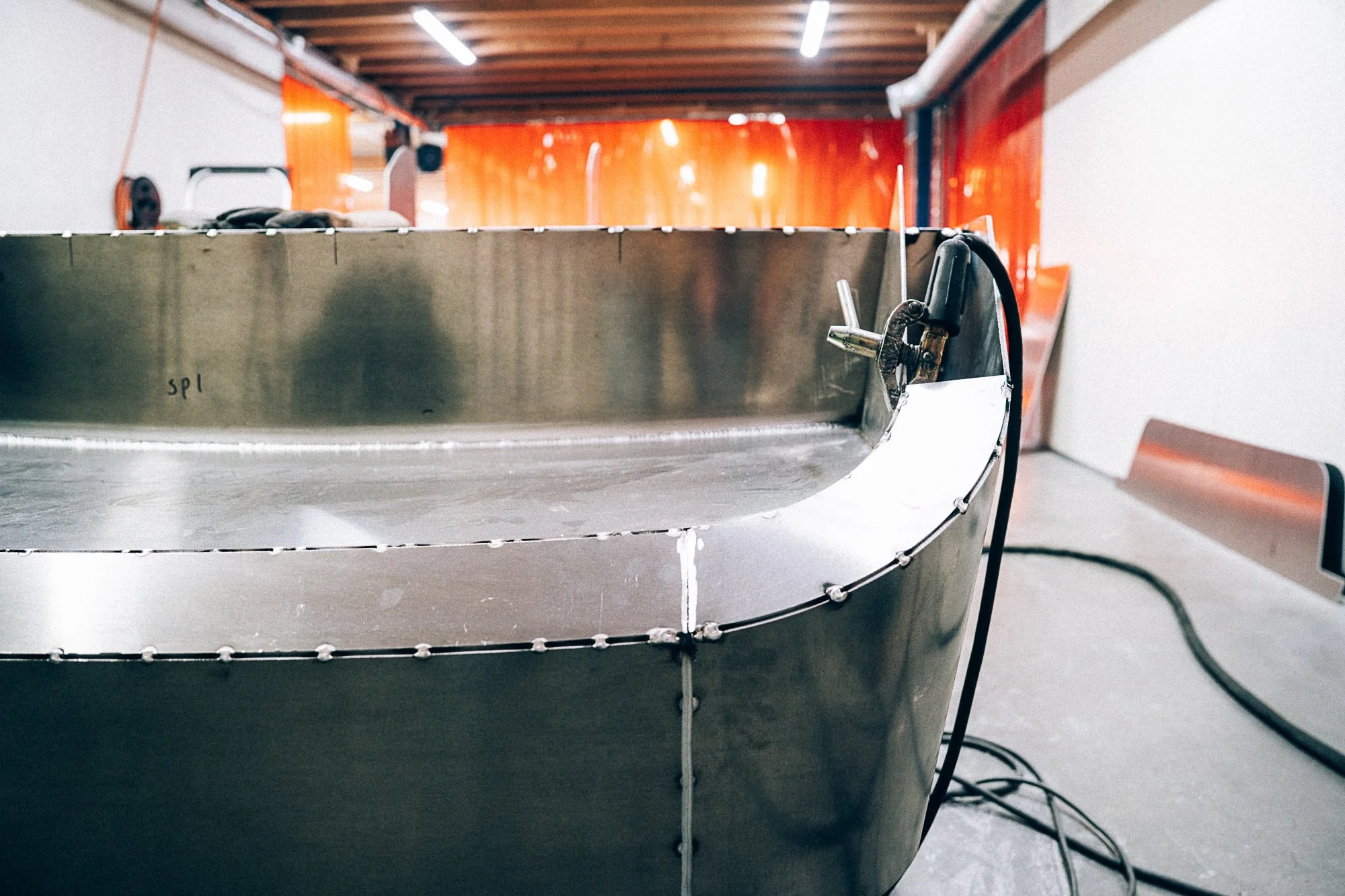 Close-up van de kont van de Nord 6 in een werkplaats met oranje afscheidingsgordijnen op de achtergrond.