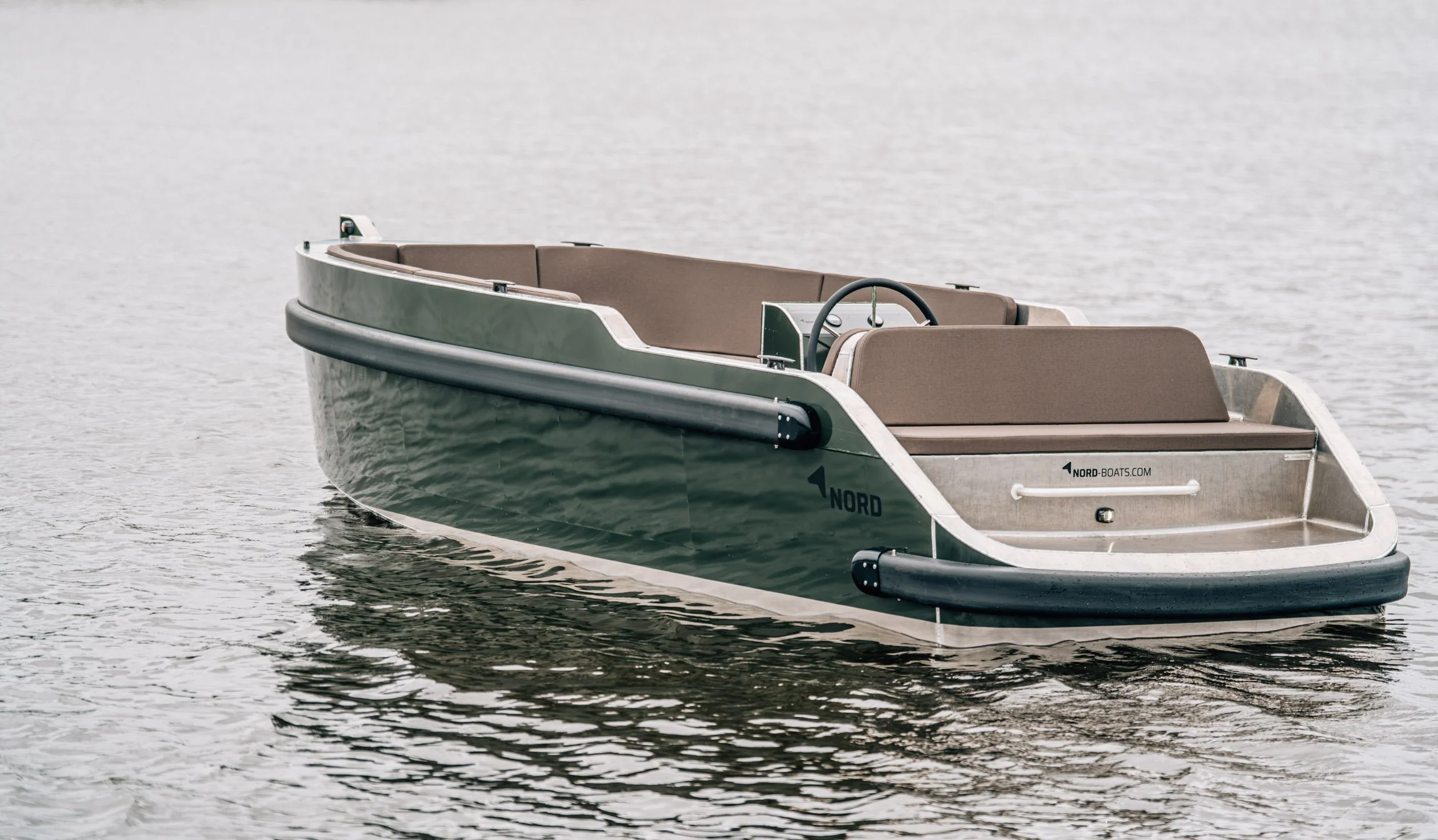 Een klein motorboot drijft op kalm water, met een beige interieur en een stuurwiel.