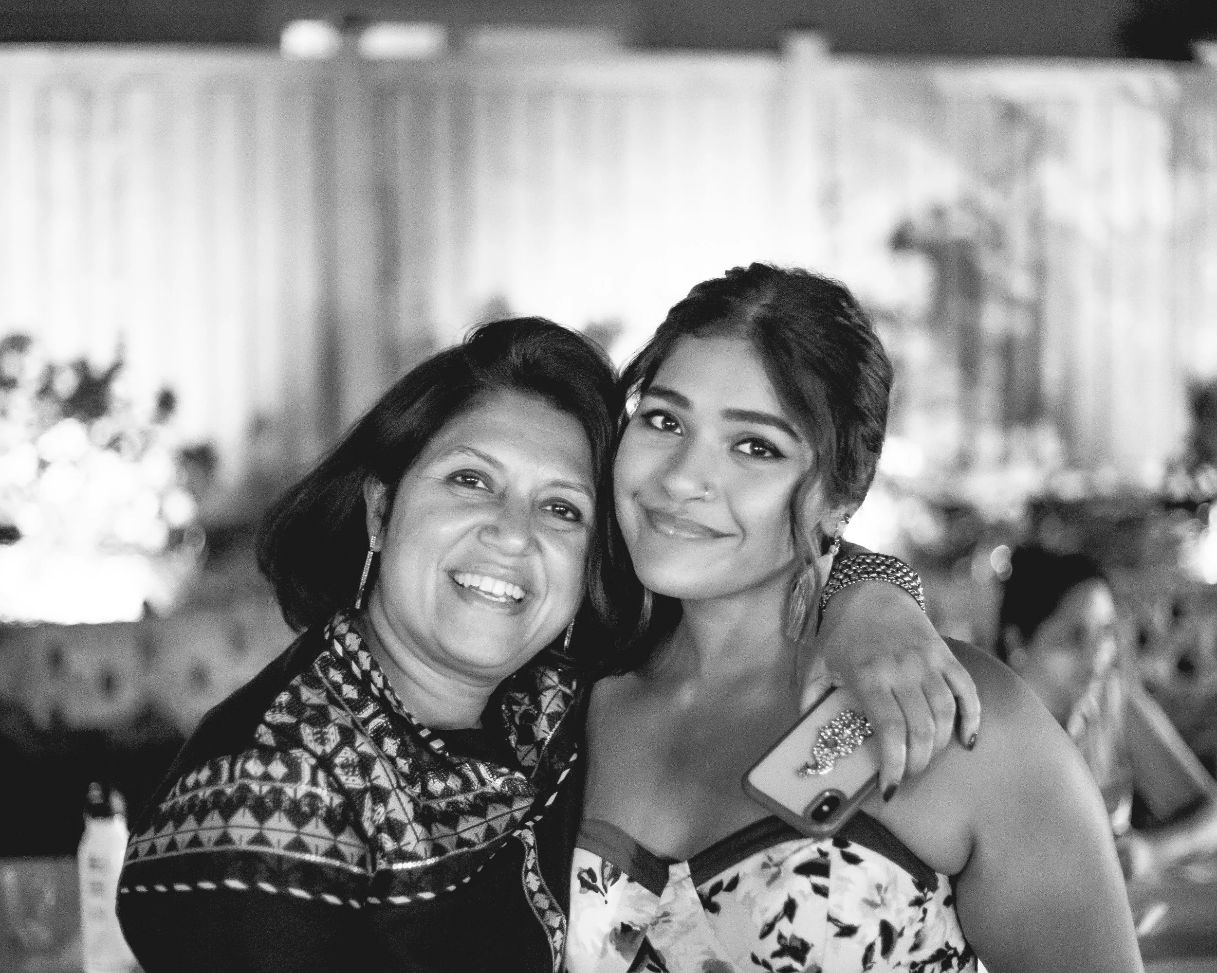 A single mother and her daughter smiling and hugging each other at a high school graduation party.