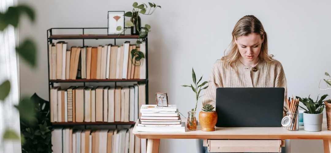 Therapeutin sitzt vor dem Laptop am Schreibtisch und schreibt einen Blogartikel für ihre Website