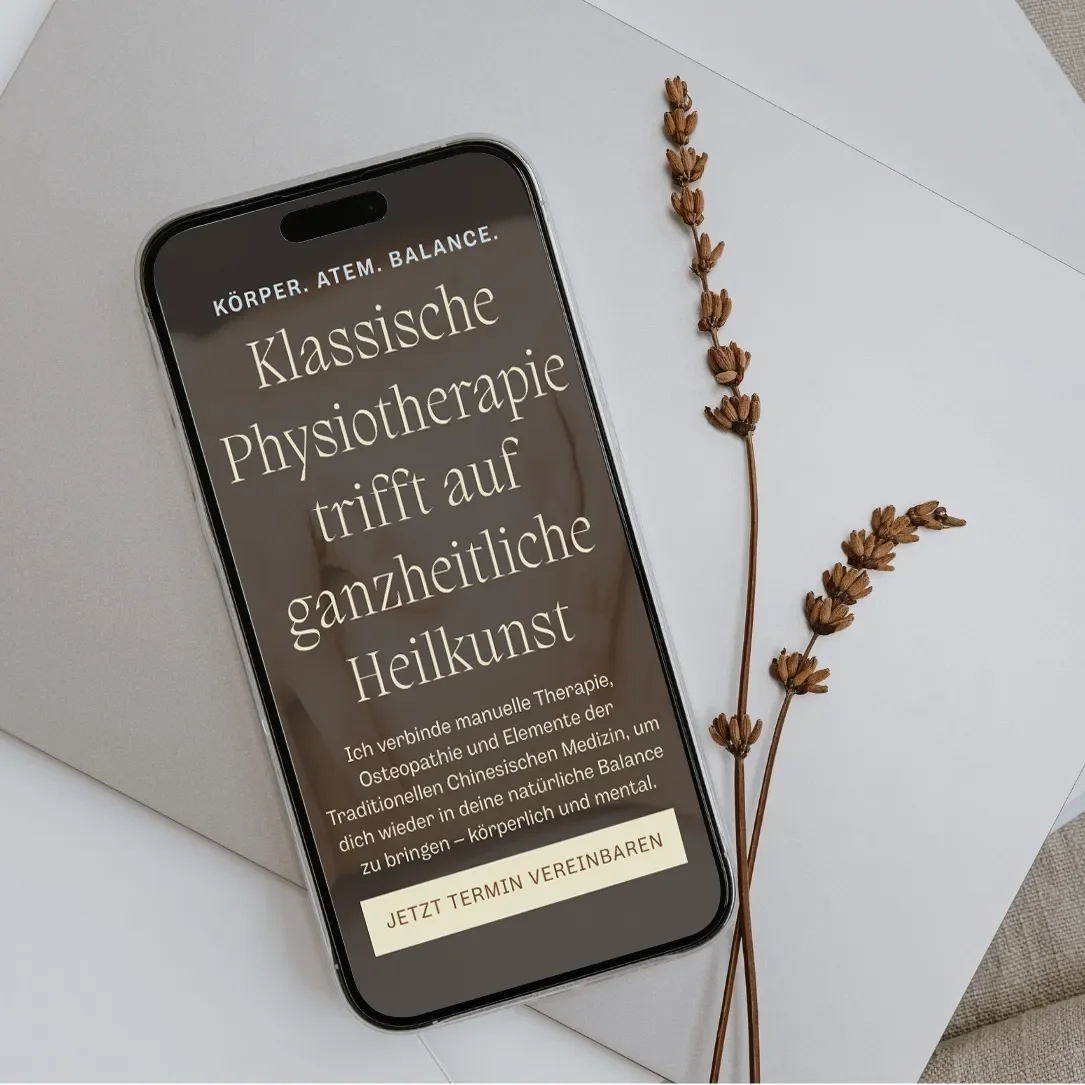 Smartphone mit Werbetext für klassische Physiotherapie auf einem weißen Hintergrund, daneben getrocknete Pflanzenzweige.