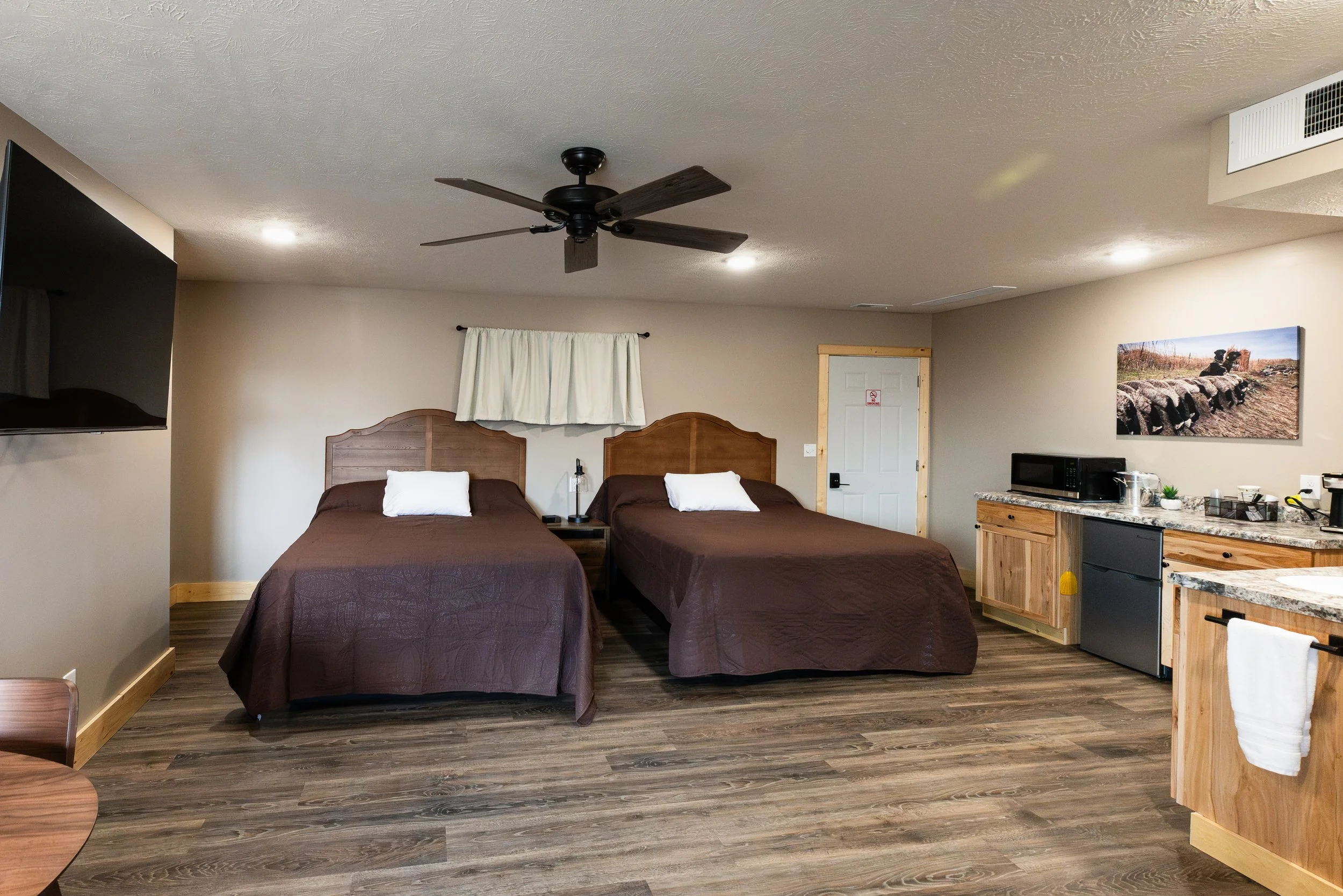 Two queen beds with brown bed spreads inside a room at Stockman's Lodge