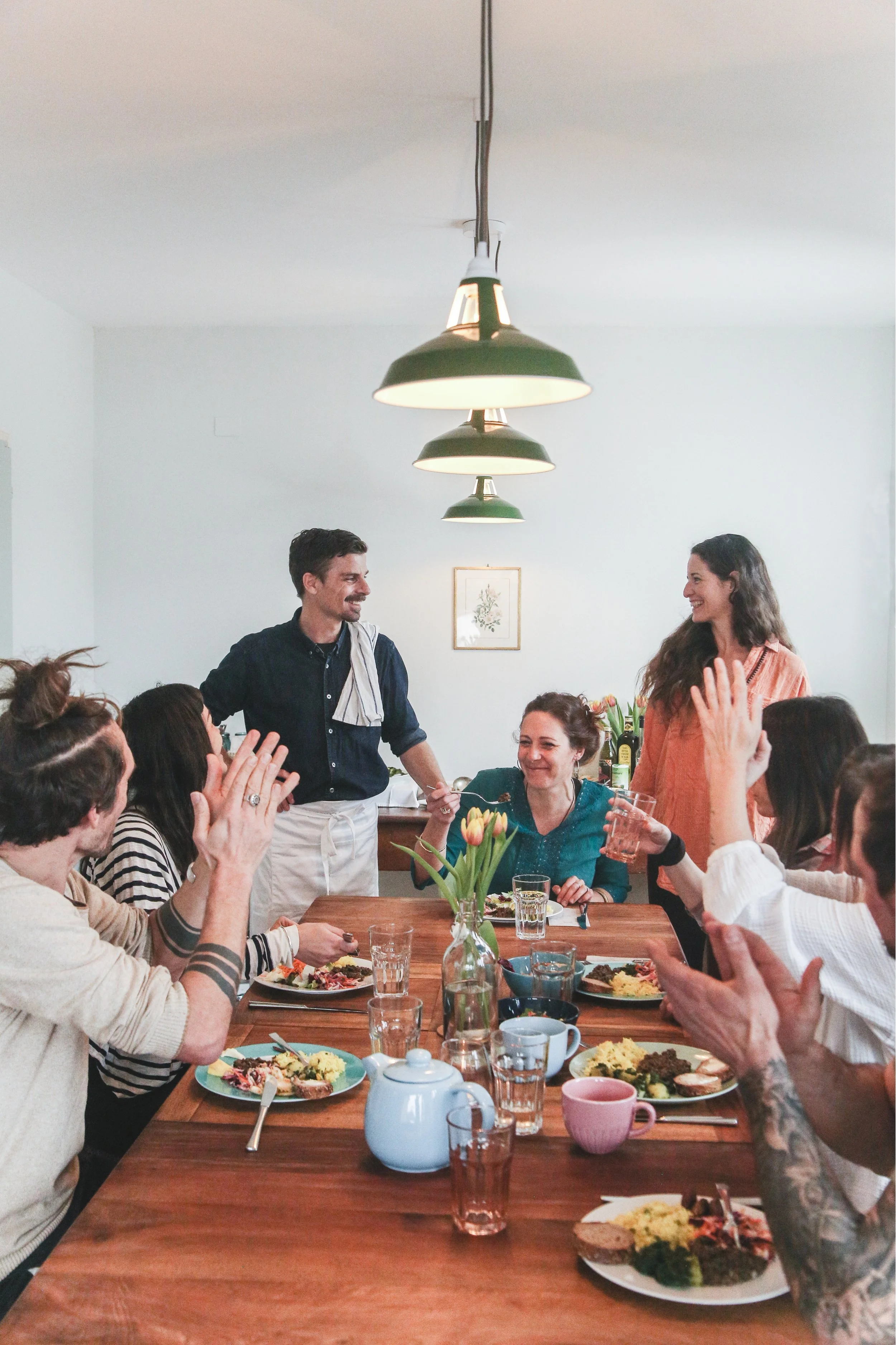 Gruppo di persone scatena, mangiando e ridendo, durante un pasto in una sala da pranzo moderna