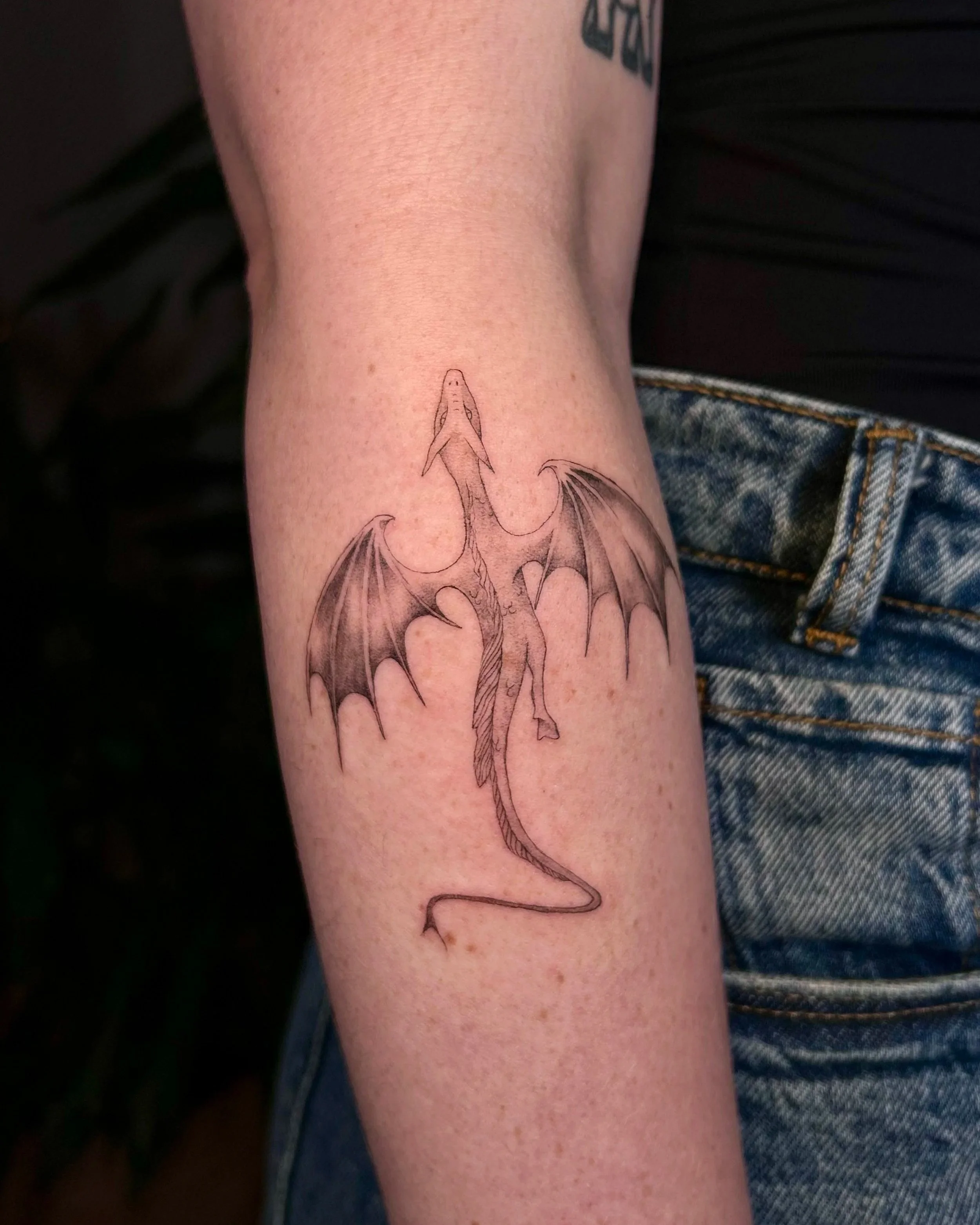Feines Fineline Drachen Tattoo mit eleganten Linien, gestochen von einer Tattoo Artist in einem queerfreundlichen Studio in Konstanz
