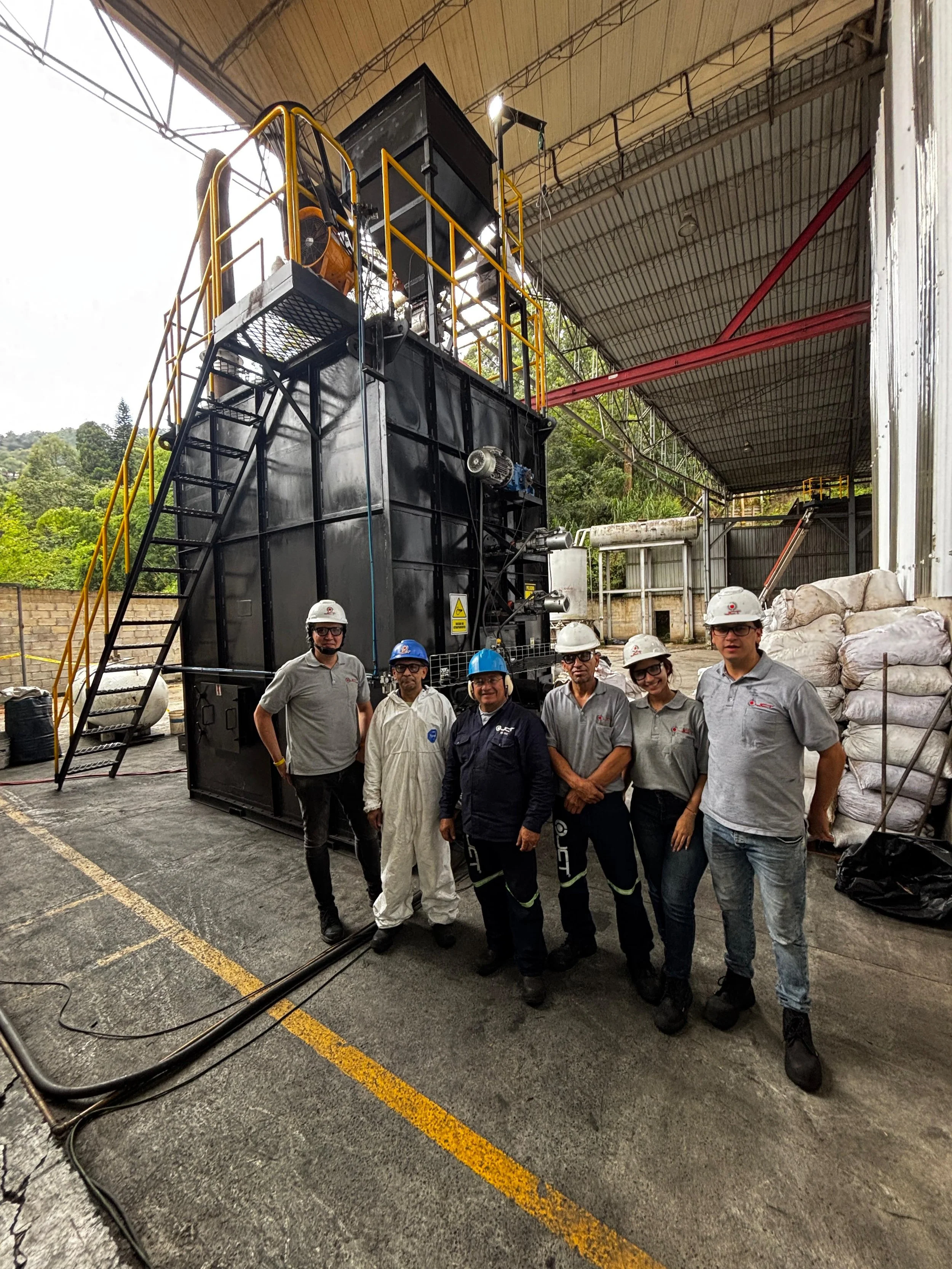 Group of five workers in front of ITER's proprietary multi-stage reactor currently operating at our manufacturing partner, JCT Calderas, location in Medellin, Colombia.