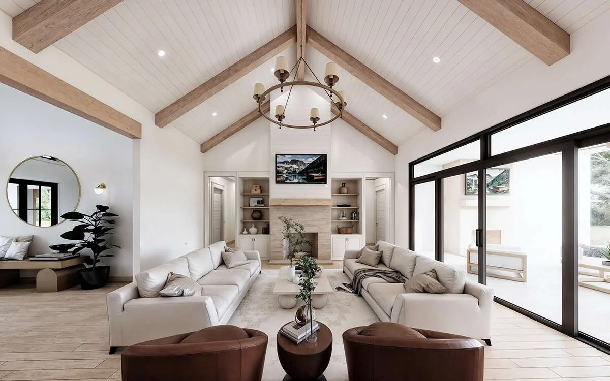 Bright living room with white sofas, a coffee table, and large sliding glass doors, with a high beamed ceiling and a fireplace with built-in shelves.