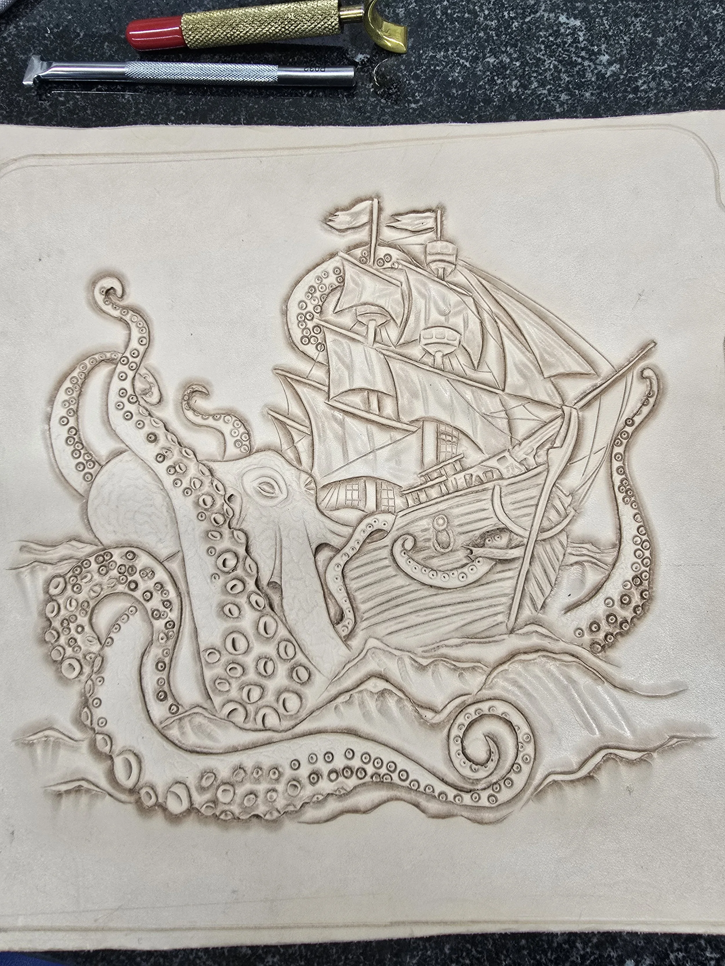 Engraved image of a ship with sails and an octopus wrapping its tentacles around the ship and in the water.