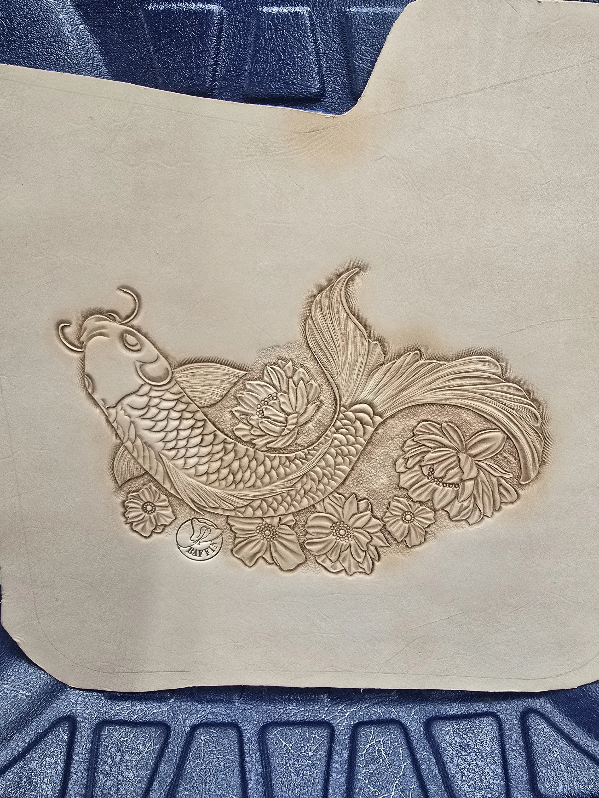 Embossed design of a fish with floral decorations on a beige surface.