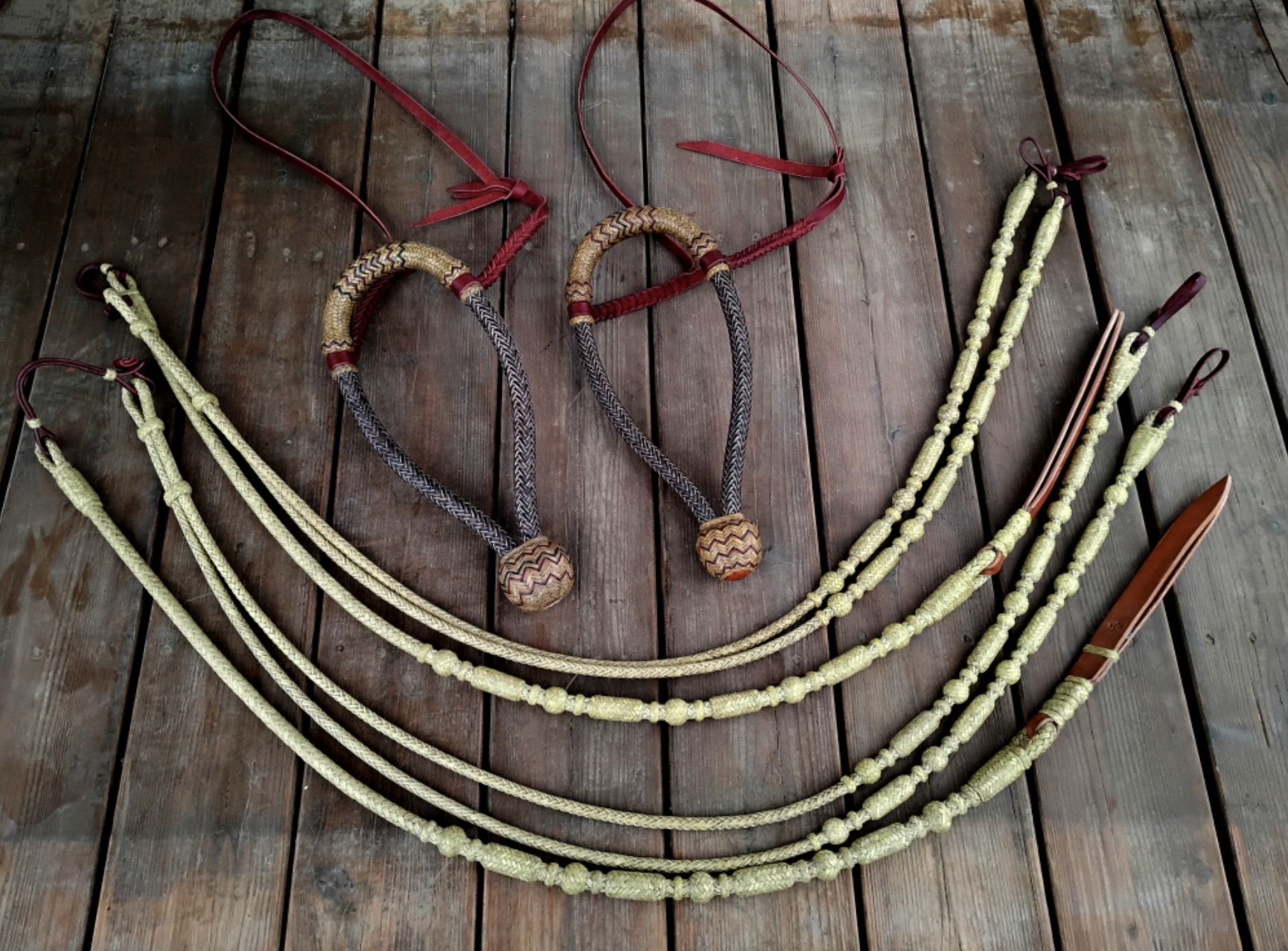 Four traditional woven belts with decorative beads and leather accents laid out on a wooden surface.