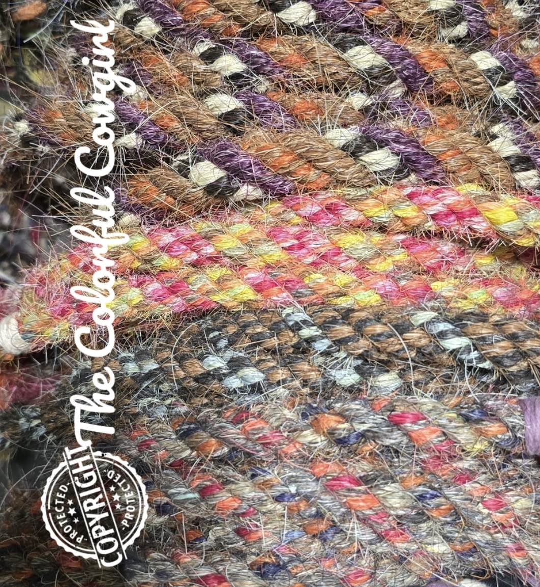 Close-up of multiple colorful braided ropes with various shades of purple, brown, pink, orange, and yellow, with some white and black accents, intertwined and overlapping.