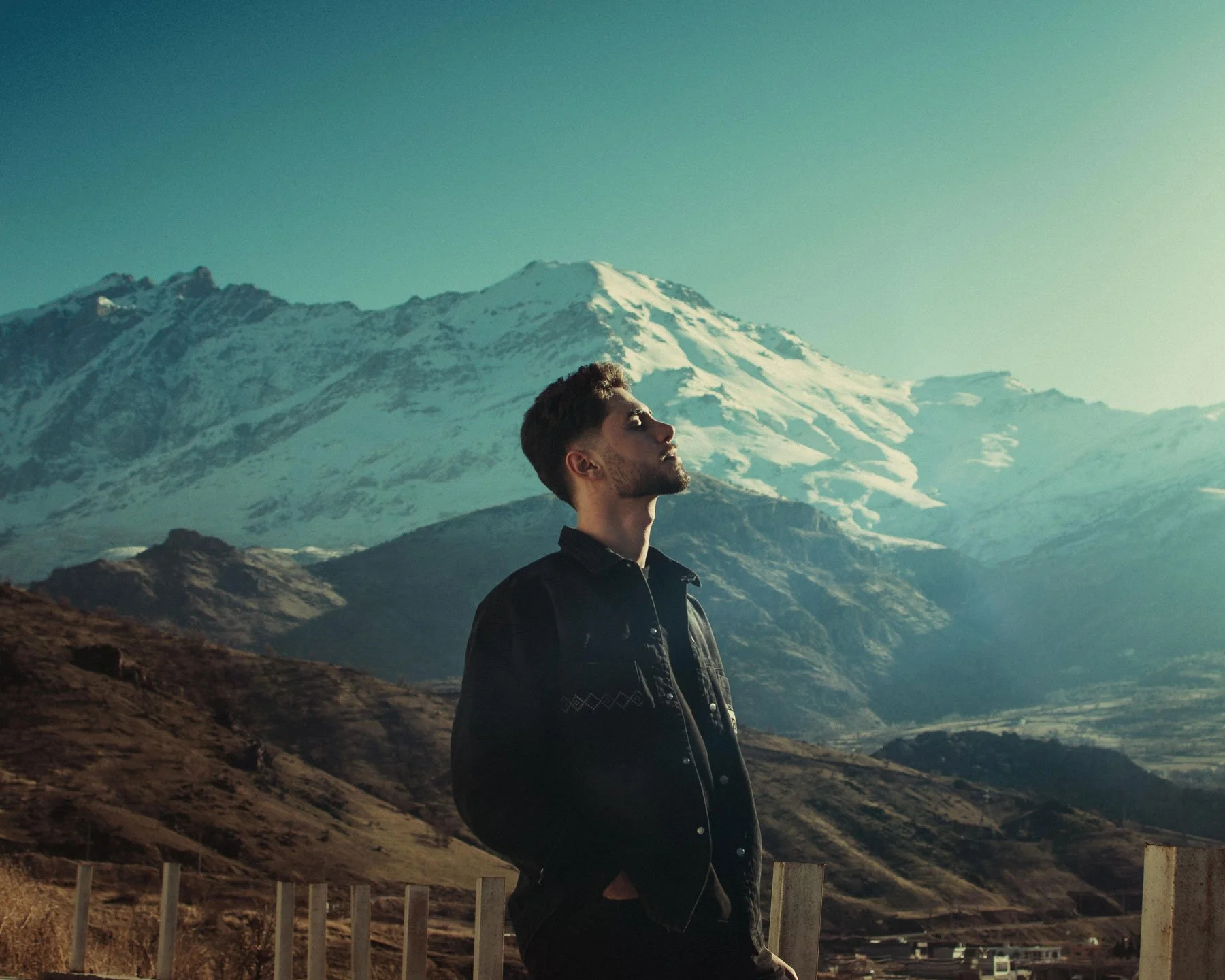 Person standing alone in a vast misty mountain landscape, representing the space between stimulus and response, and the quality of presence available when a leader slows down enough to choose
