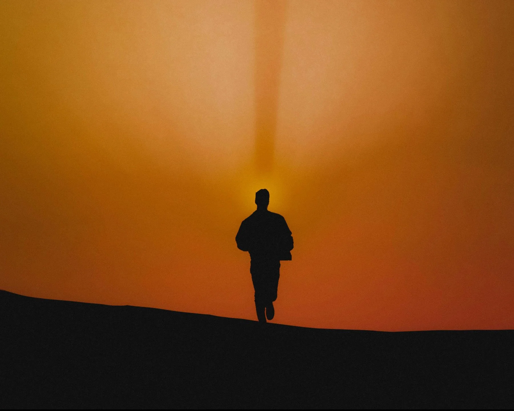 Lone figure silhouetted against a deep orange sunset on an open landscape, representing the clarity that arrives on the other side of profound personal loss