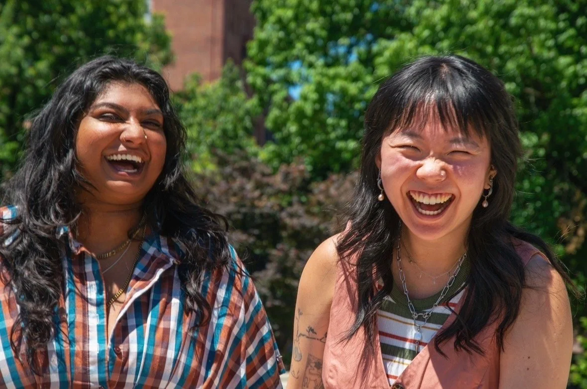 Two Queer and Asian, affirming psycho-therapists laughing together outside in Baltimore, Maryland.