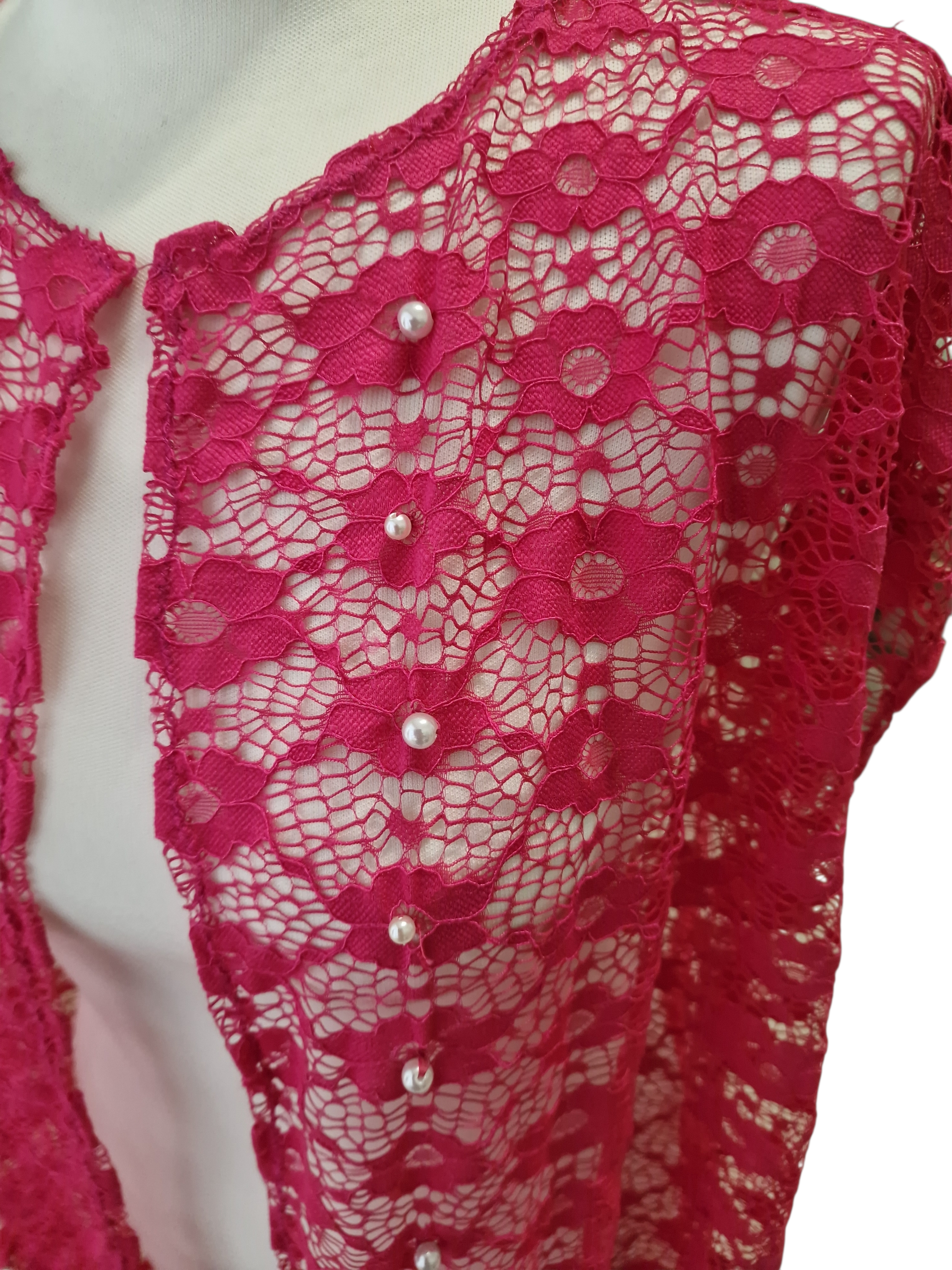 dettaglio dell'applicazione di perle ricamate a mano nel pizzo fuxia