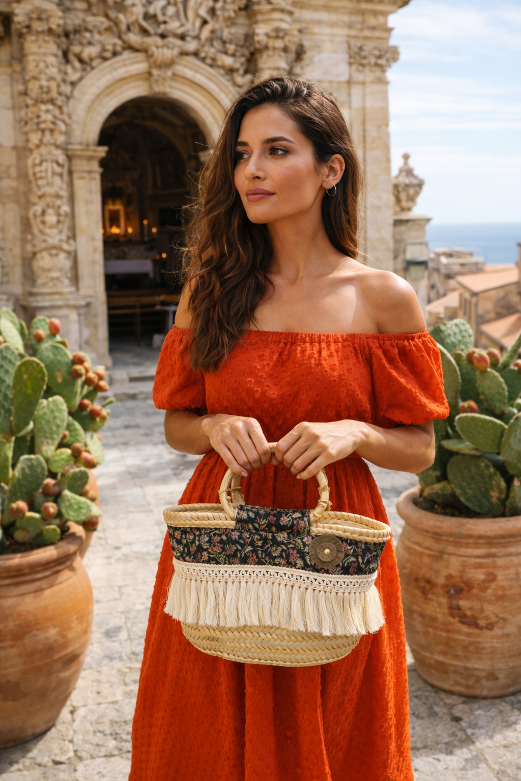 modella in un contesto siciliano barocco che indossa la coffa borsa romanzina rivestita in tessuto floreale e manici in bambù