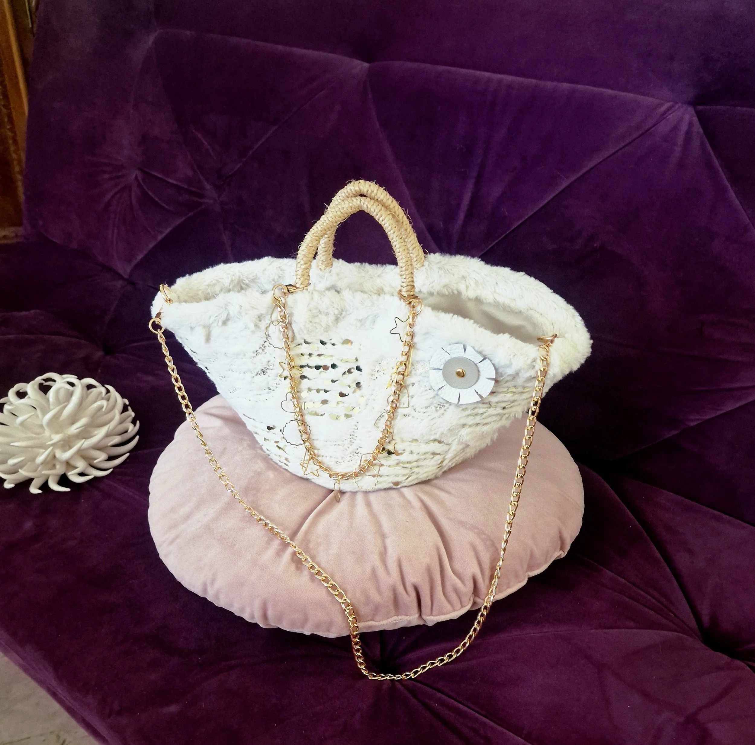 Borsa "Aurora" Ammuri esposta su fondo viola, rivestita in ecopelliccia panna e fiori bianchi in pelle naturale, doppia catena