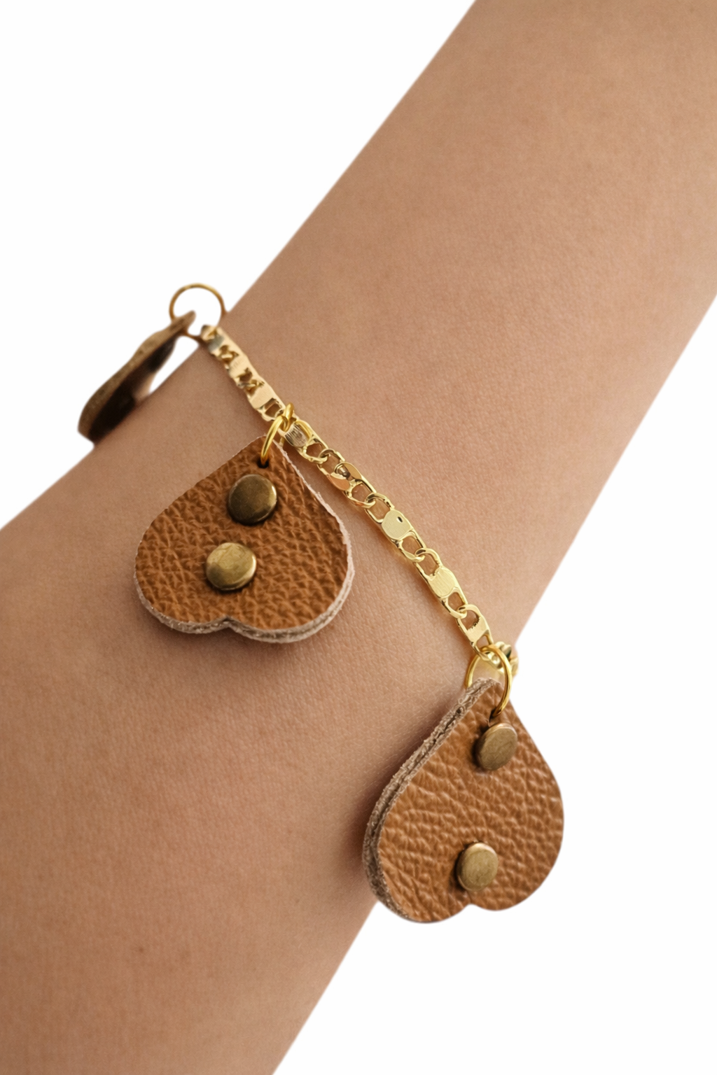 Close-up bracciale artigianale con cuoricini pendenti in pelle color cuoio e catena dorata leggera