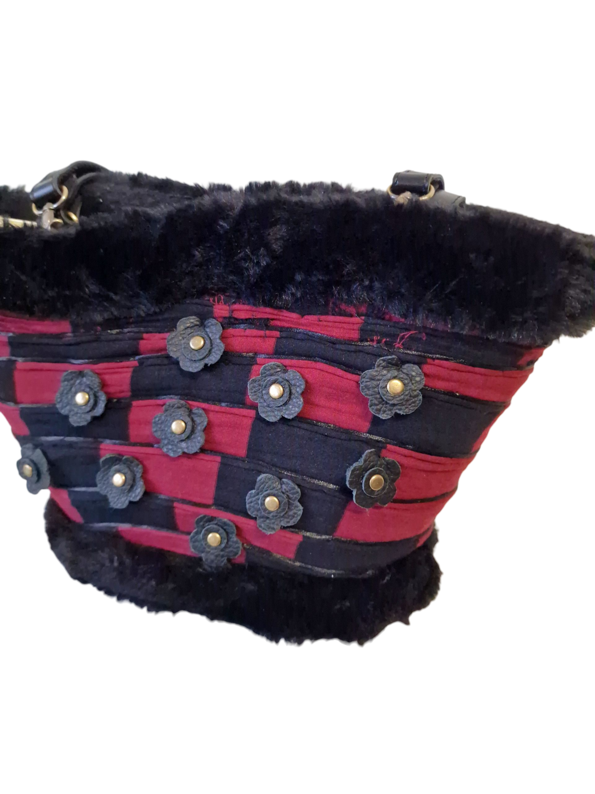 Dettaglio della coffa Elison con fiori in pelle nera e borchie dorate su patchwork rosso e nero.