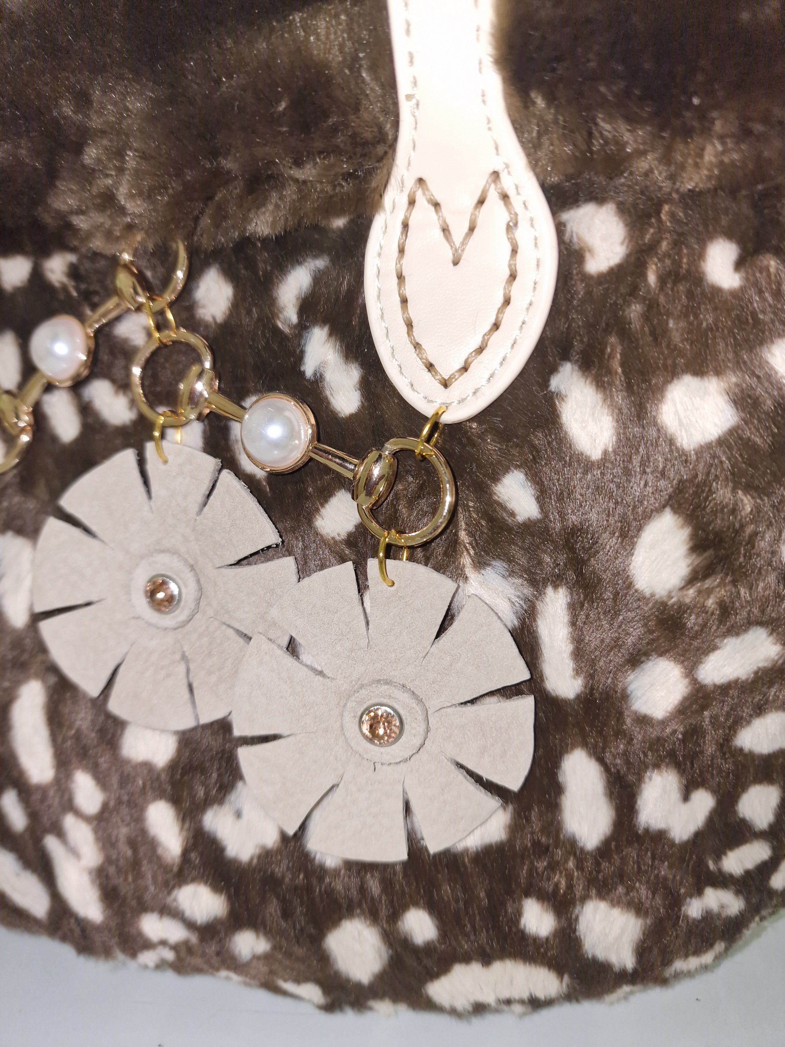 dettaglio della borsa con charm di cerchi dorati, perle e fiori in pelle beige fatti interamente a mano