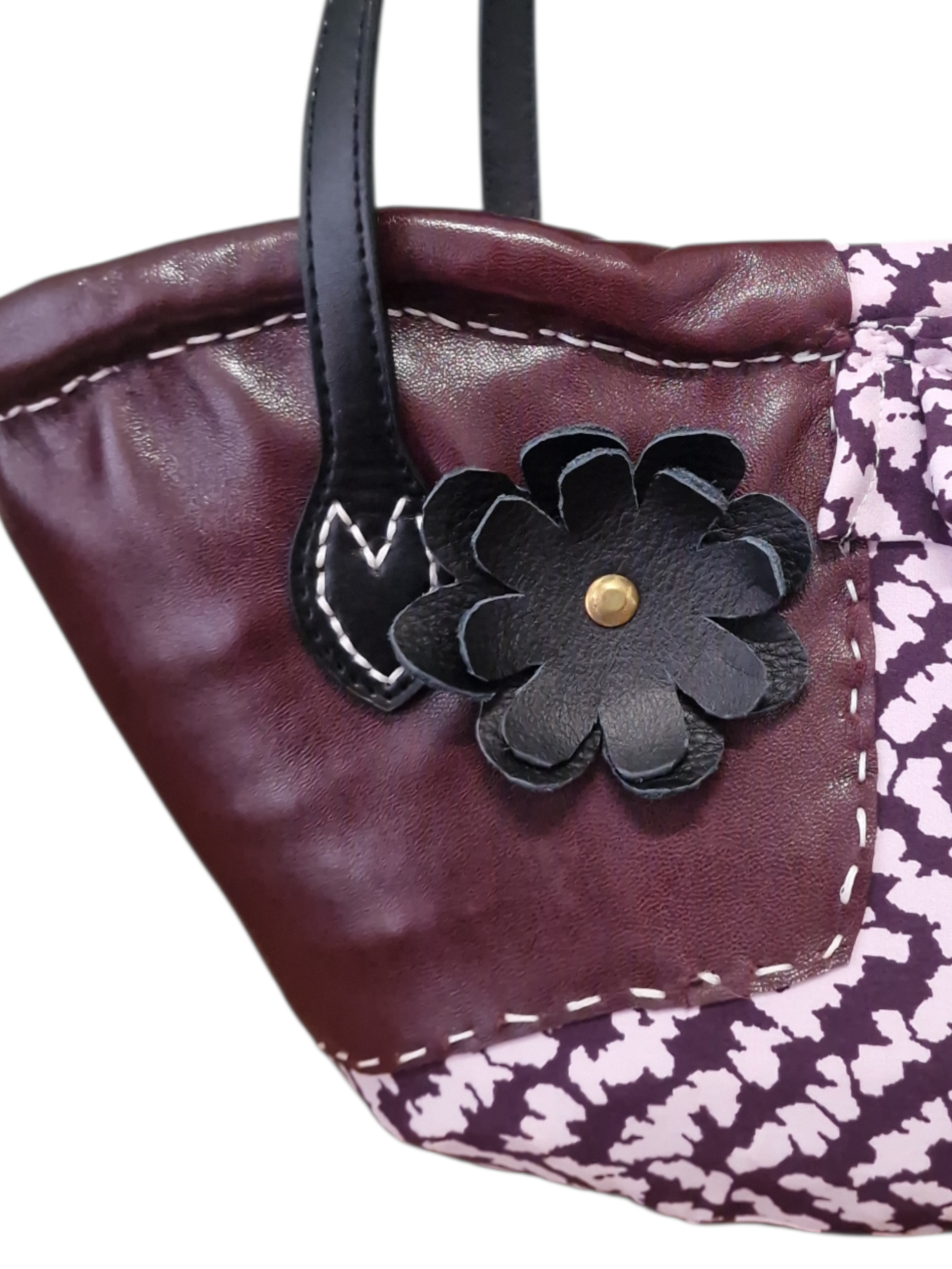 Primo piano del fiore Ammuri in pelle applicato sulla coffa, con lavorazione artigianale e cuciture visibili.