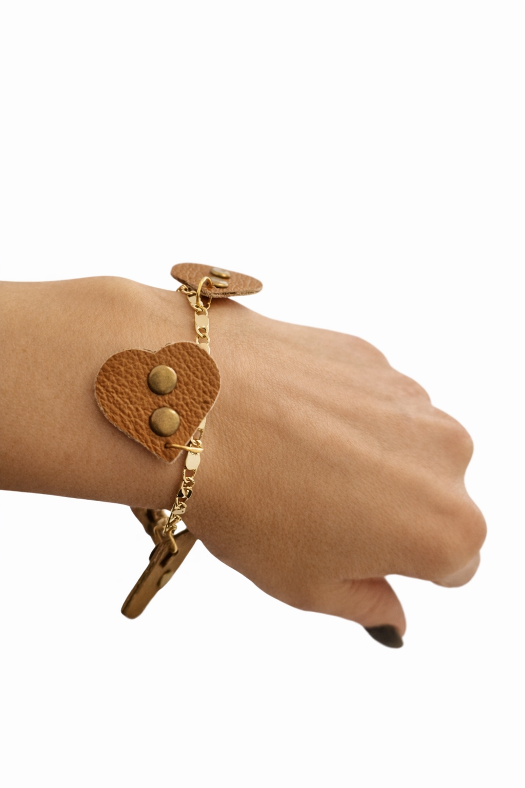 Bracciale Ammuri con cuori in pelle color cuoio e bottoncini bronzo indossato al polso su catenella dorata